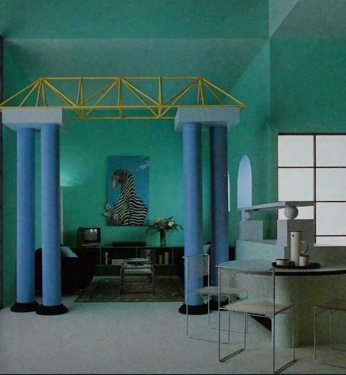 A distinctive 1980s interior design living space with teal walls, blue pillars, and a unique architectural element.