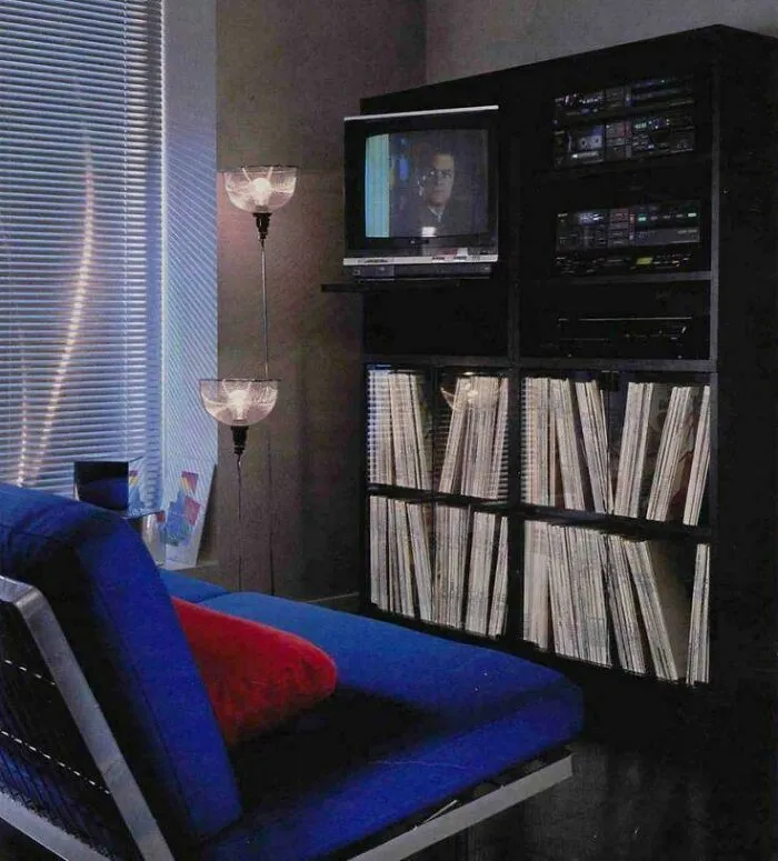 A cozy 1970s interior design with a blue sofa, record collection, and a TV, showcasing vintage style.