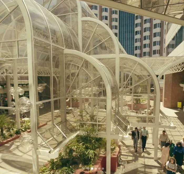 A grand atrium showcasing striking 1980s interior design with soaring glass and white structural arches.
