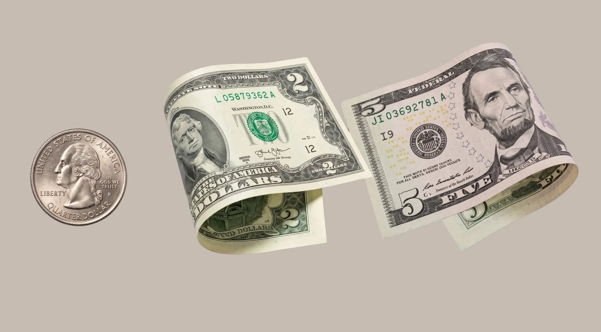 A U.S. quarter, two-dollar bill, and five-dollar bill on a grey background. This is a 40% club question.
