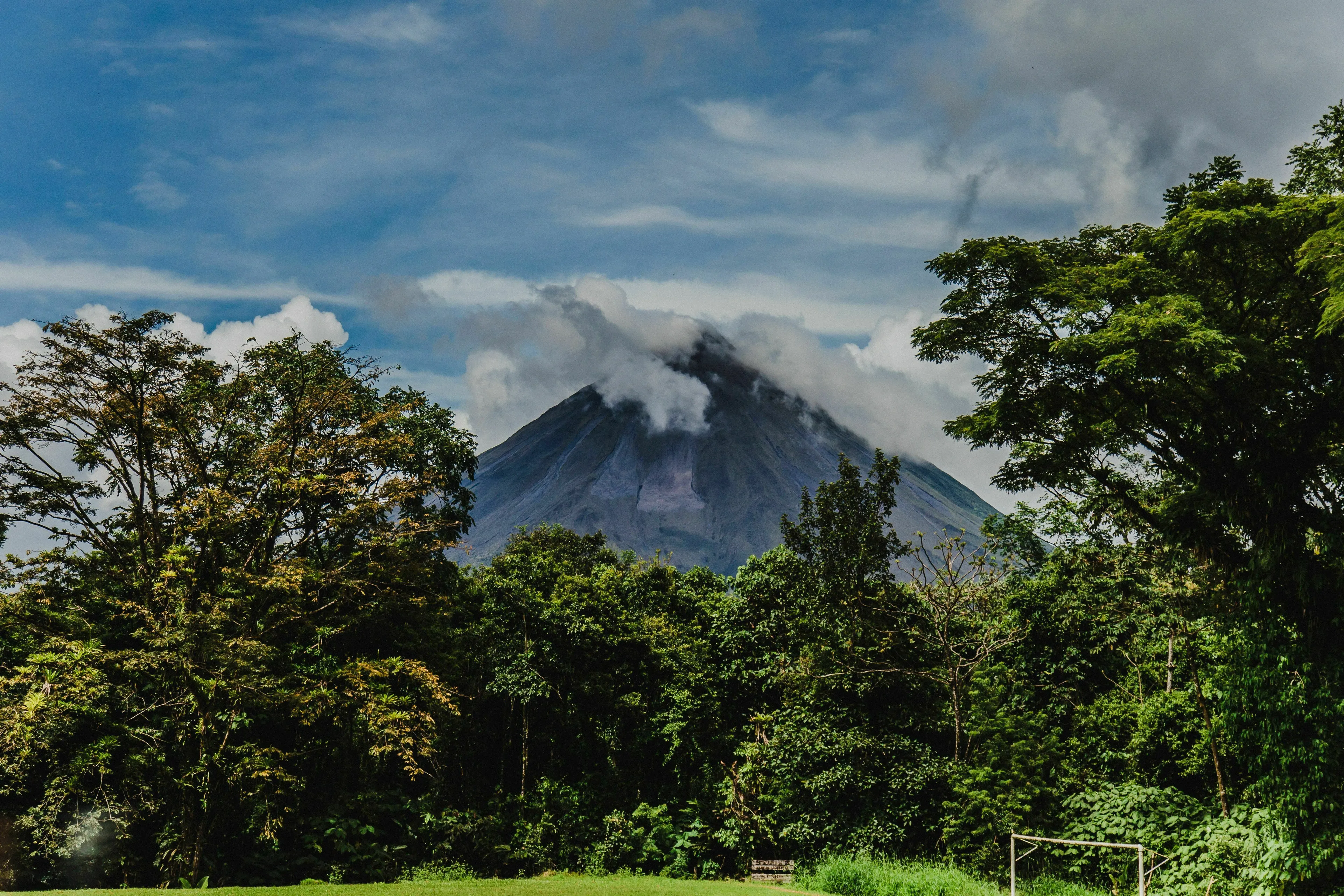 A majestic volcano surrounded by lush green trees, part of a general knowledge odd one out challenge.