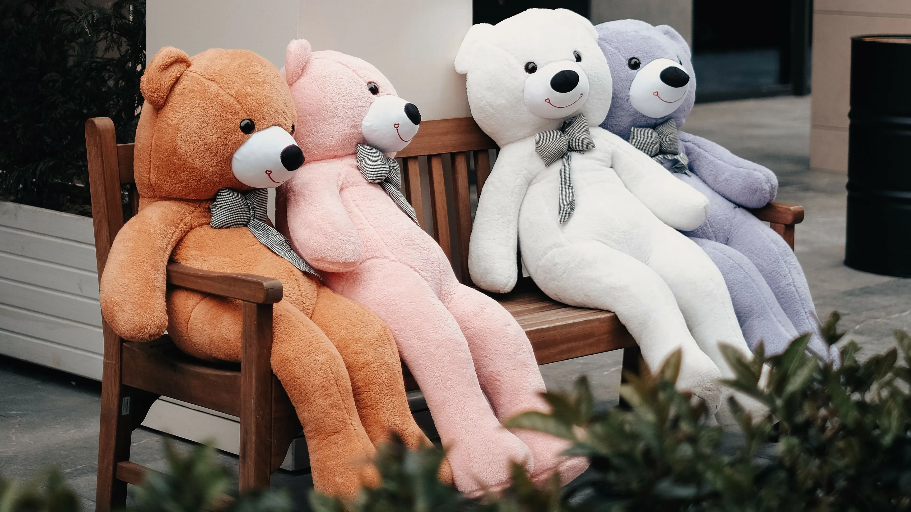 Large, colorful teddy bears sitting on a bench, posing a tricky question about a bear.