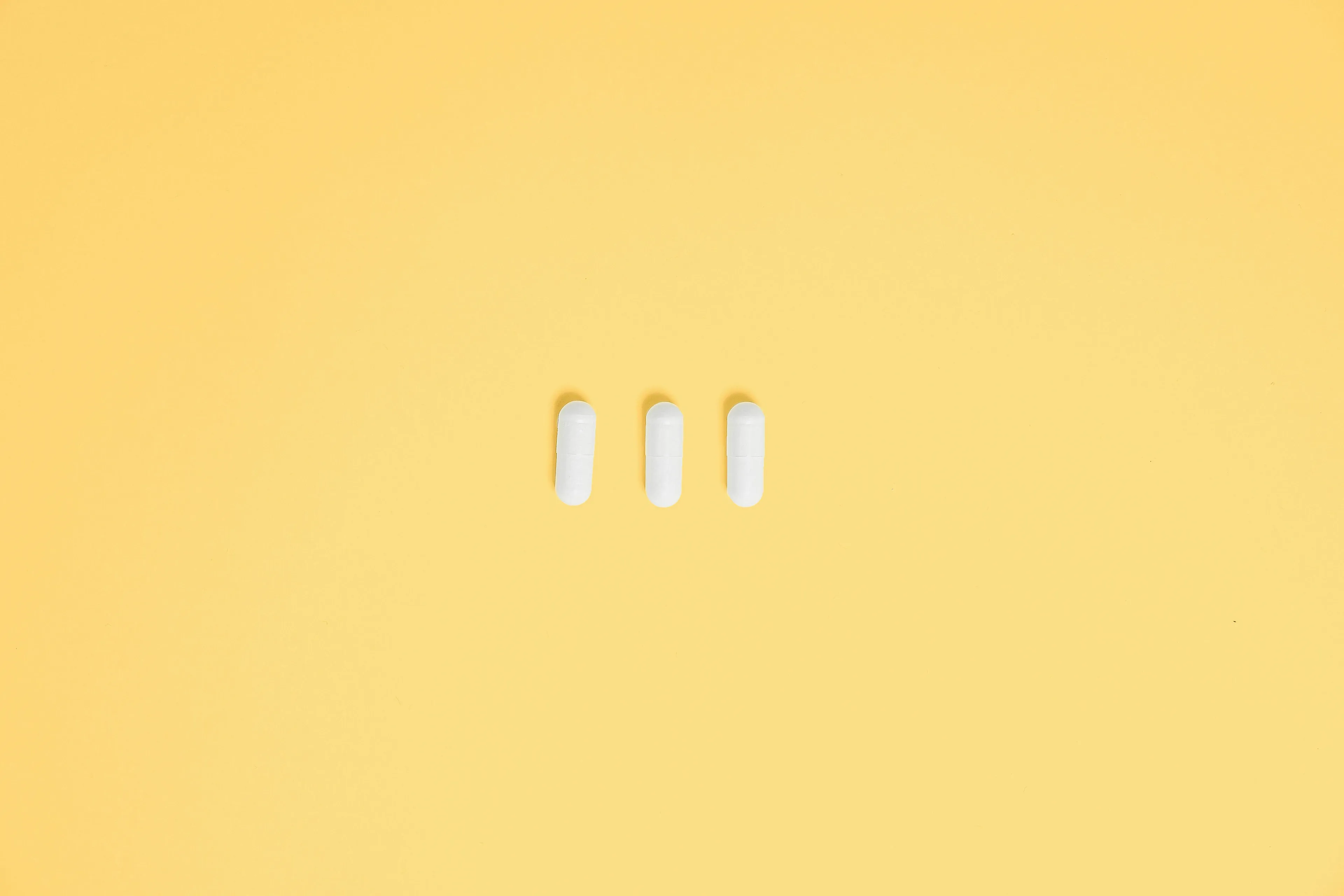 Three white pills laid out on a yellow surface, illustrating a tricky question about medication.