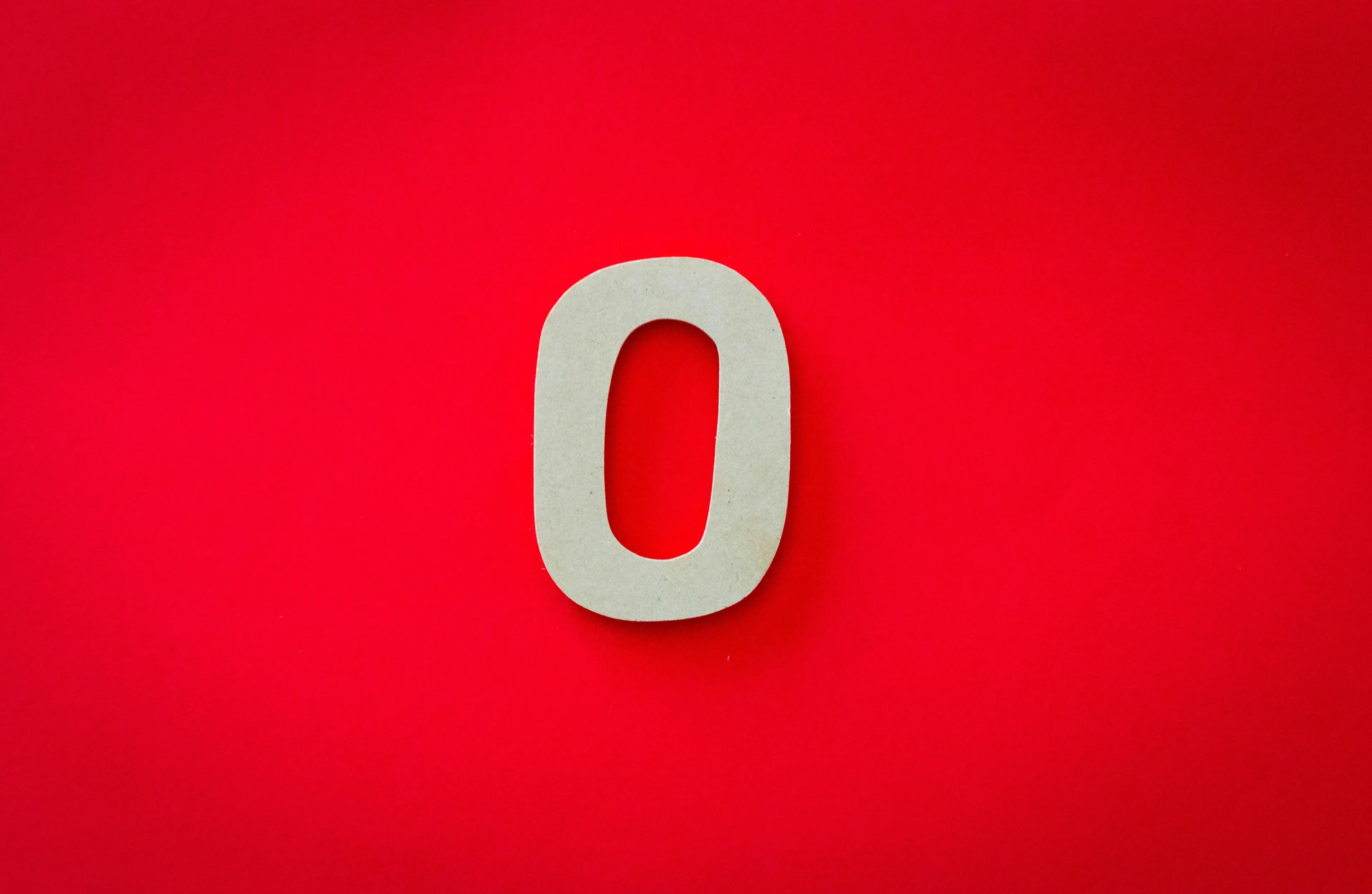A large wooden number zero on a vibrant red background, addressing the even or odd number query.