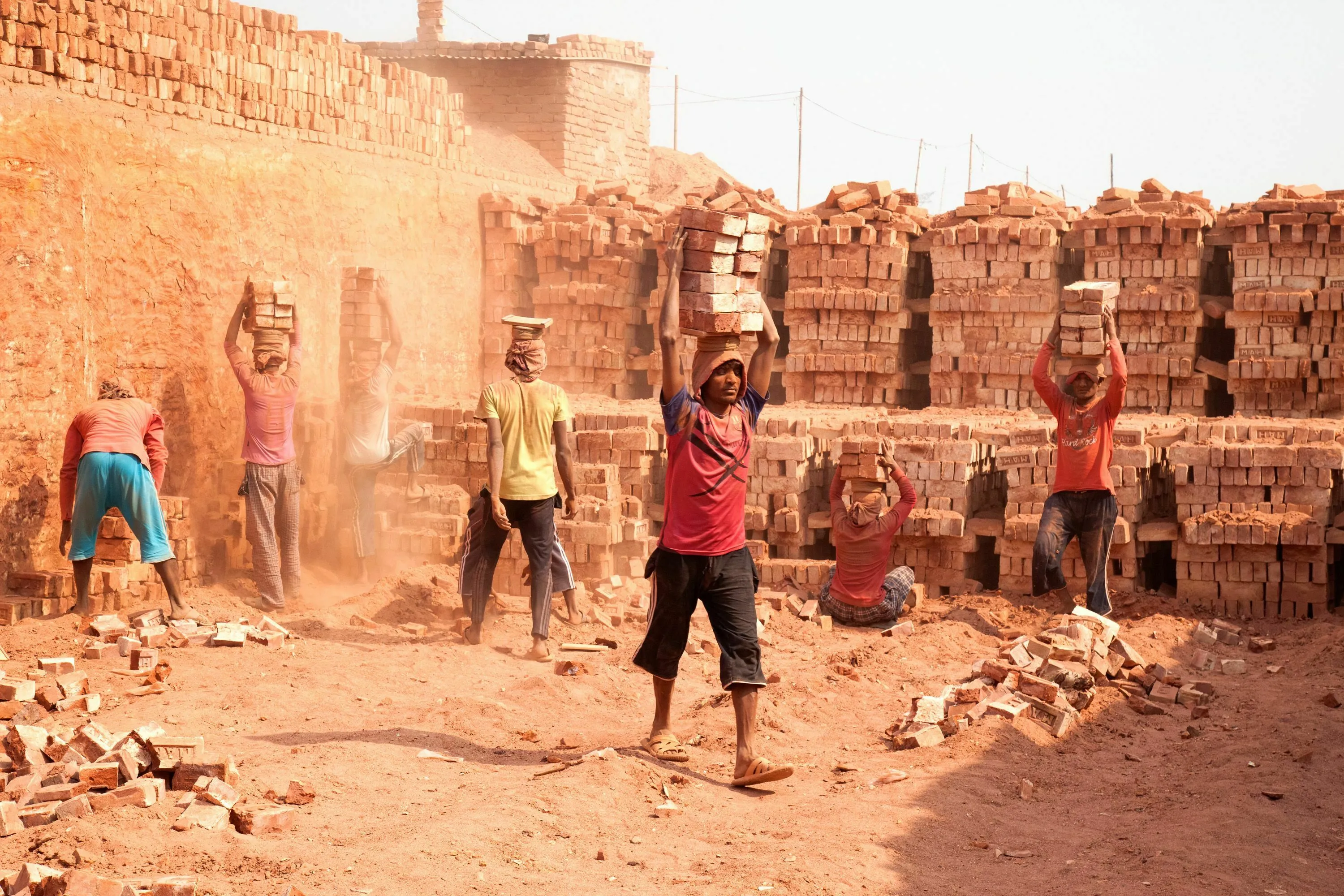 Workers building a brick wall in a dusty, sunny environment illustrates a tricky question about construction time.
