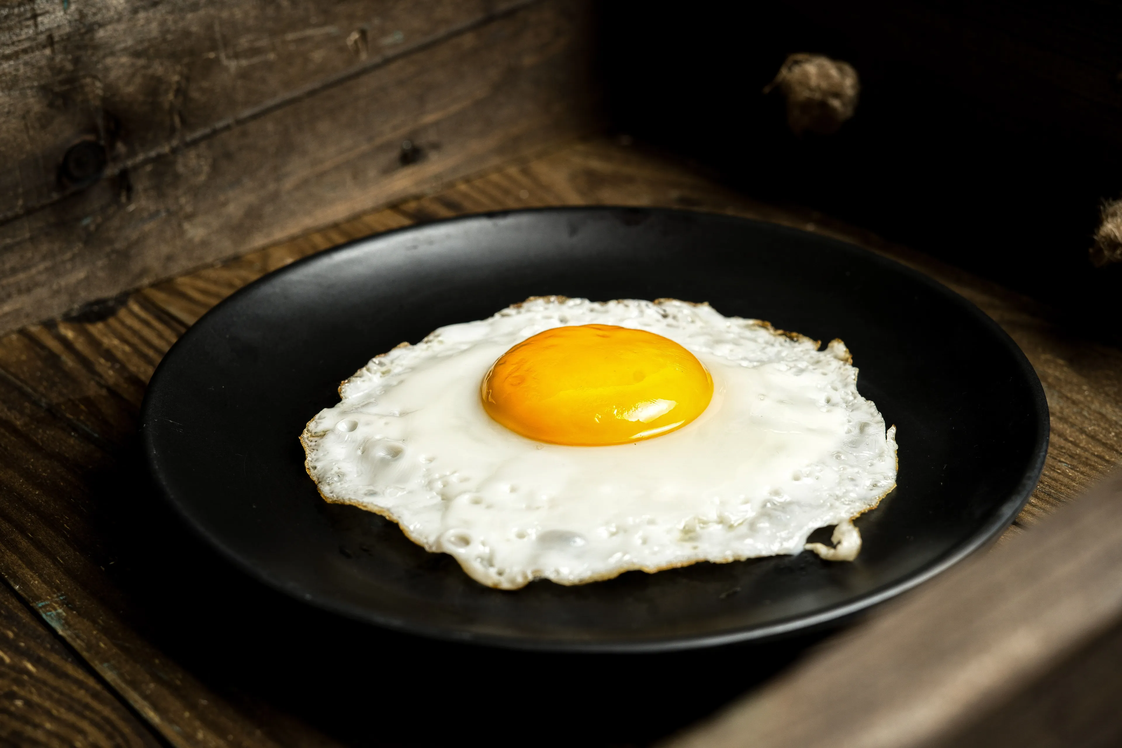 A fried egg on a black plate. Answering tricky questions about spelling.
