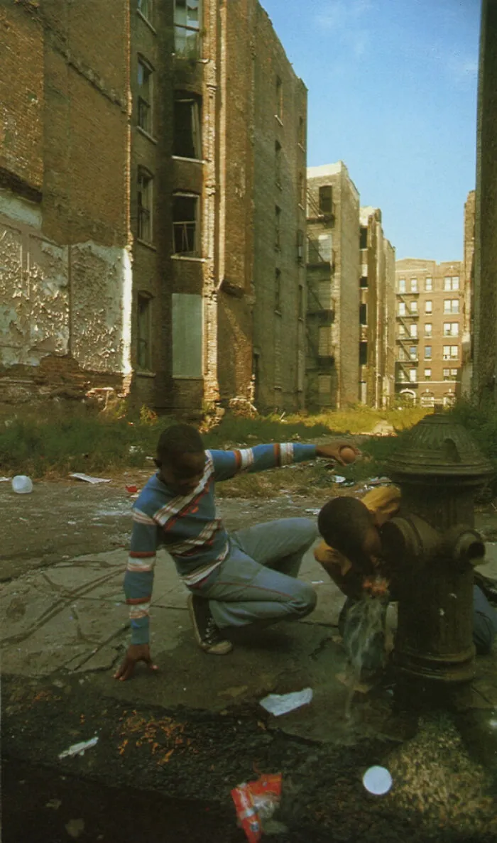 Historical photos: Two boys playing with a fire hydrant amidst crumbling buildings, showing a past that will remain alive.