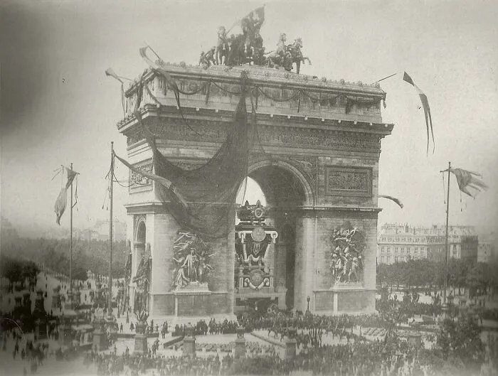 Historical photos: A large crowd gathers around the Arc de Triomphe, showcasing a past public event.