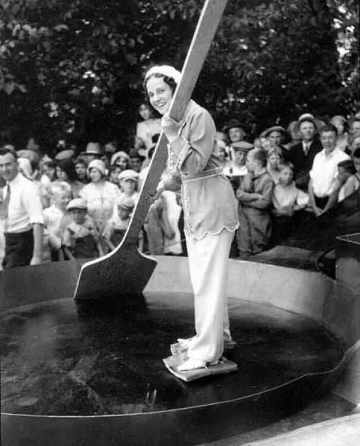 A historical photo shows a woman stirring a giant pot with an oversized spoon for a crowd, a fun past event.