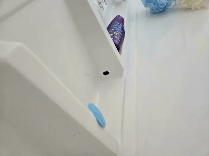 A white shower caddy with a purple bottle of shampoo and a blue sponge, revealing a common household item that needs help fixing things.