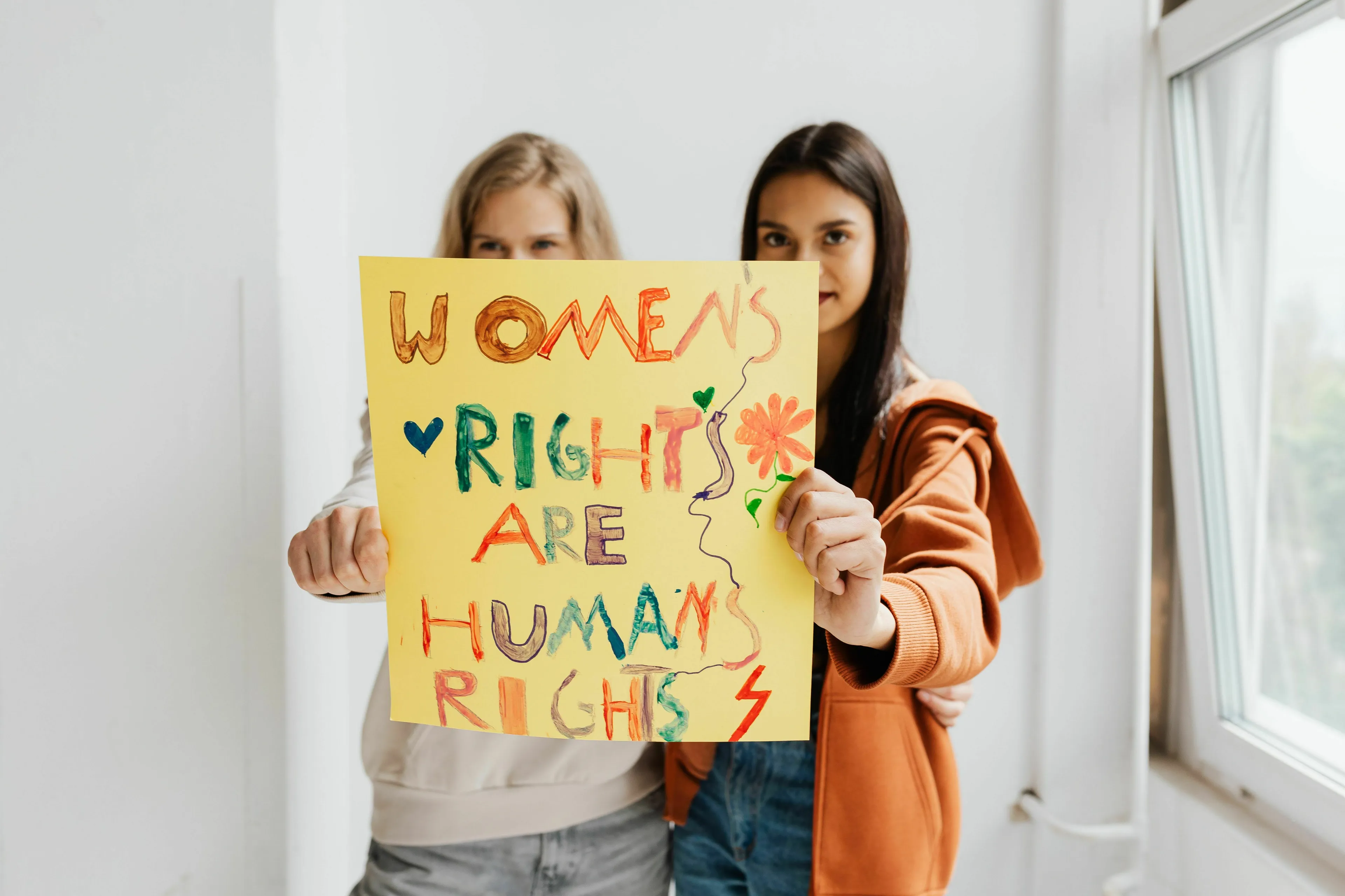 Two women holding a sign that reads Women's Rights are Human Rights, relating to women's right to vote in national elections.