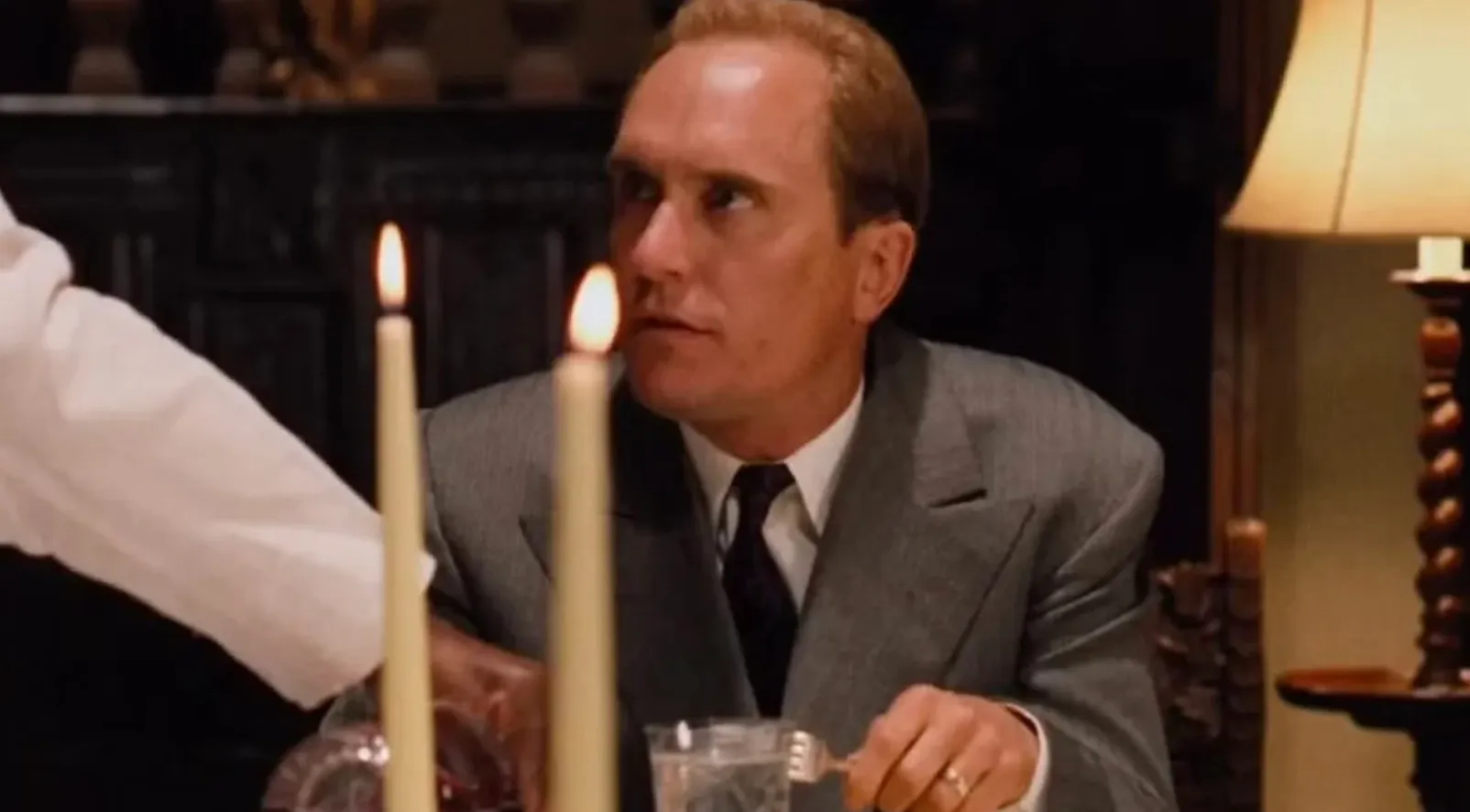 A man from The Godfather (1972) at a table, with candles in the foreground, connected to a general knowledge test about fruit as a symbol.