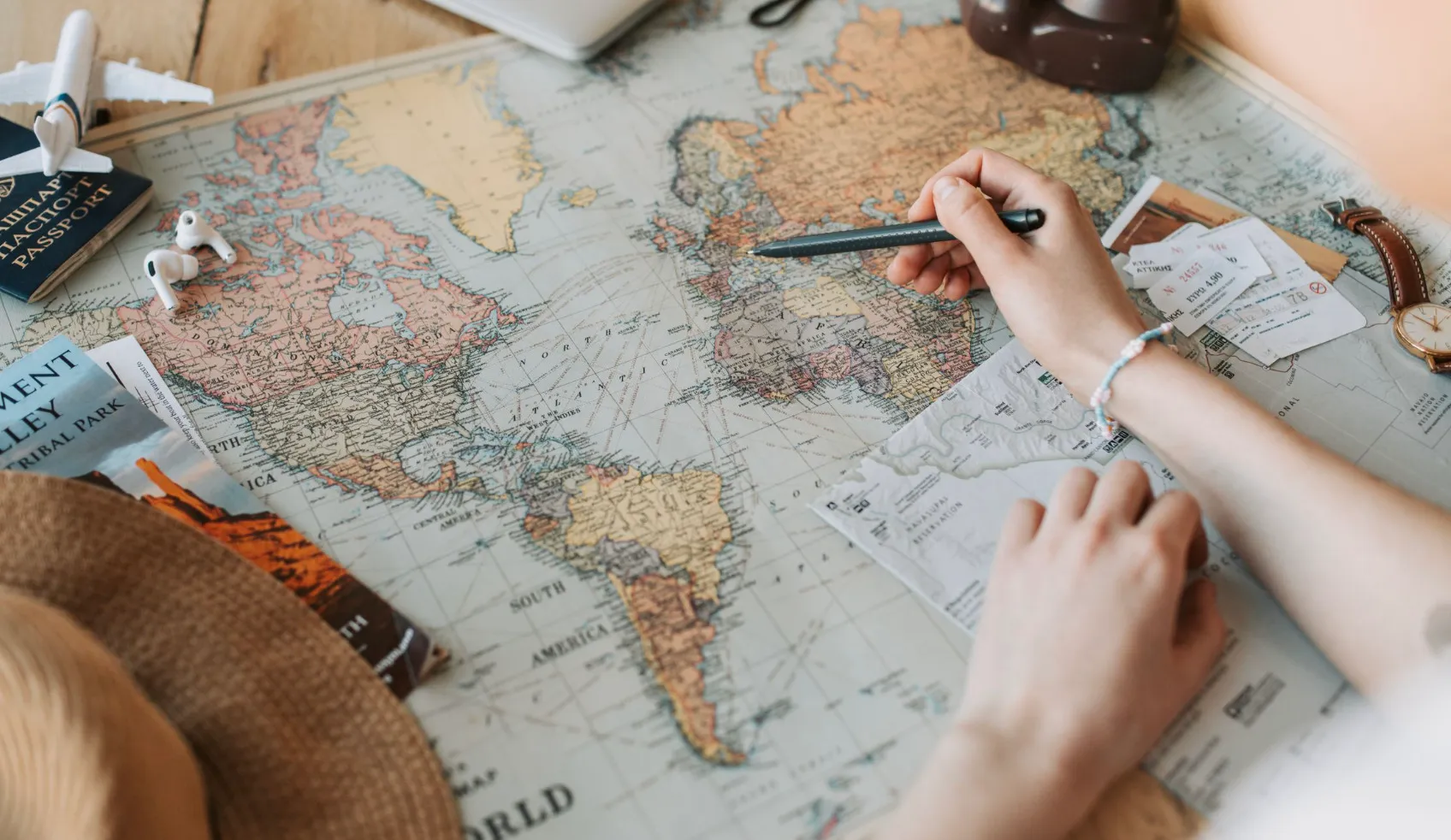 Hands pointing to a world map, indicating countries sharing a land border for a high IQ general knowledge test.