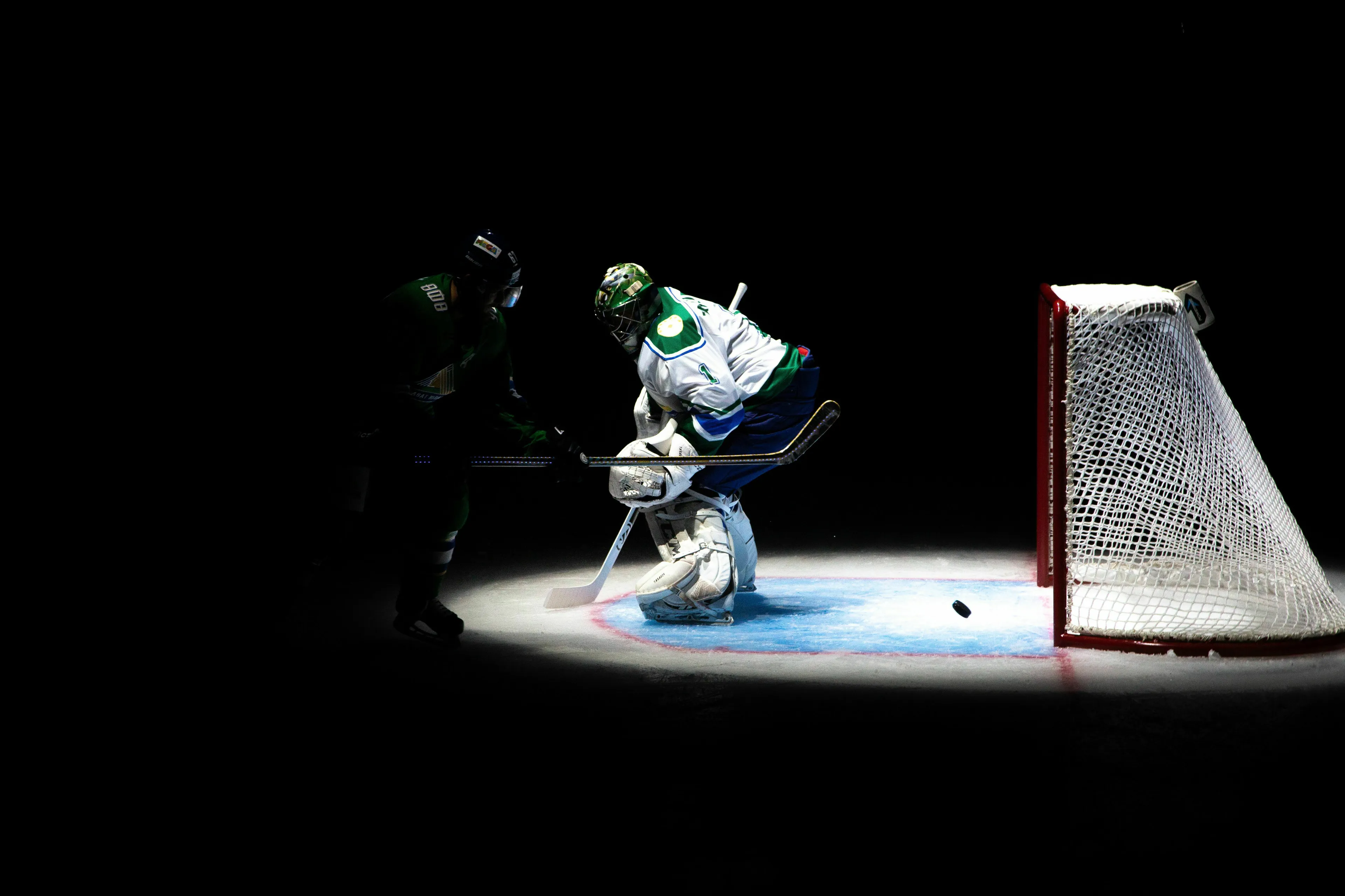 Ice hockey players on a dark rink with a puck near the goal, representing the general knowledge quiz.