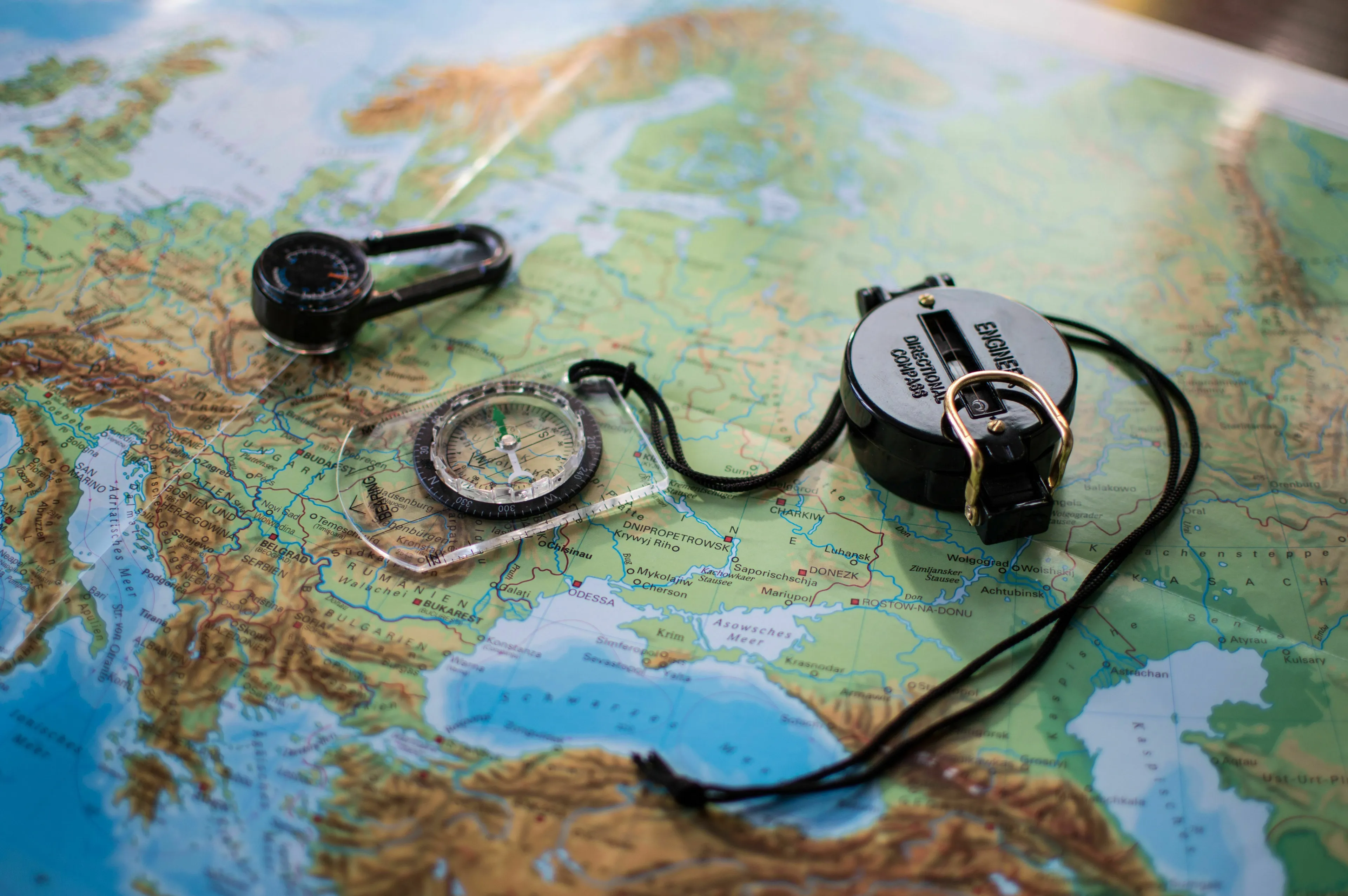 Two compasses lie on a detailed map, indicating directions. This image is for a general knowledge quiz on geography.