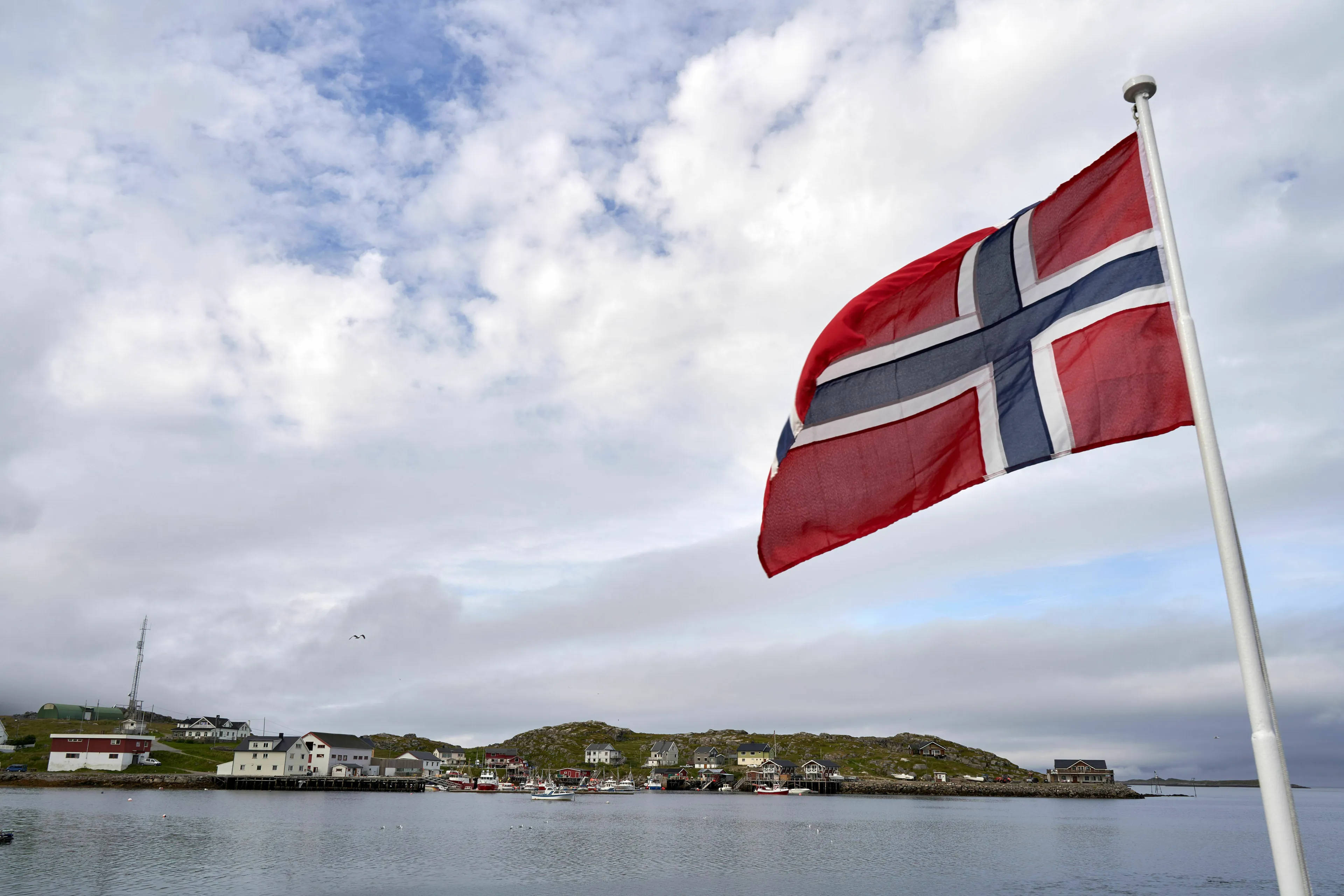 Four Letter General Knowledge Quiz: A Norway flag waving over a coastal town, hinting at its capital.