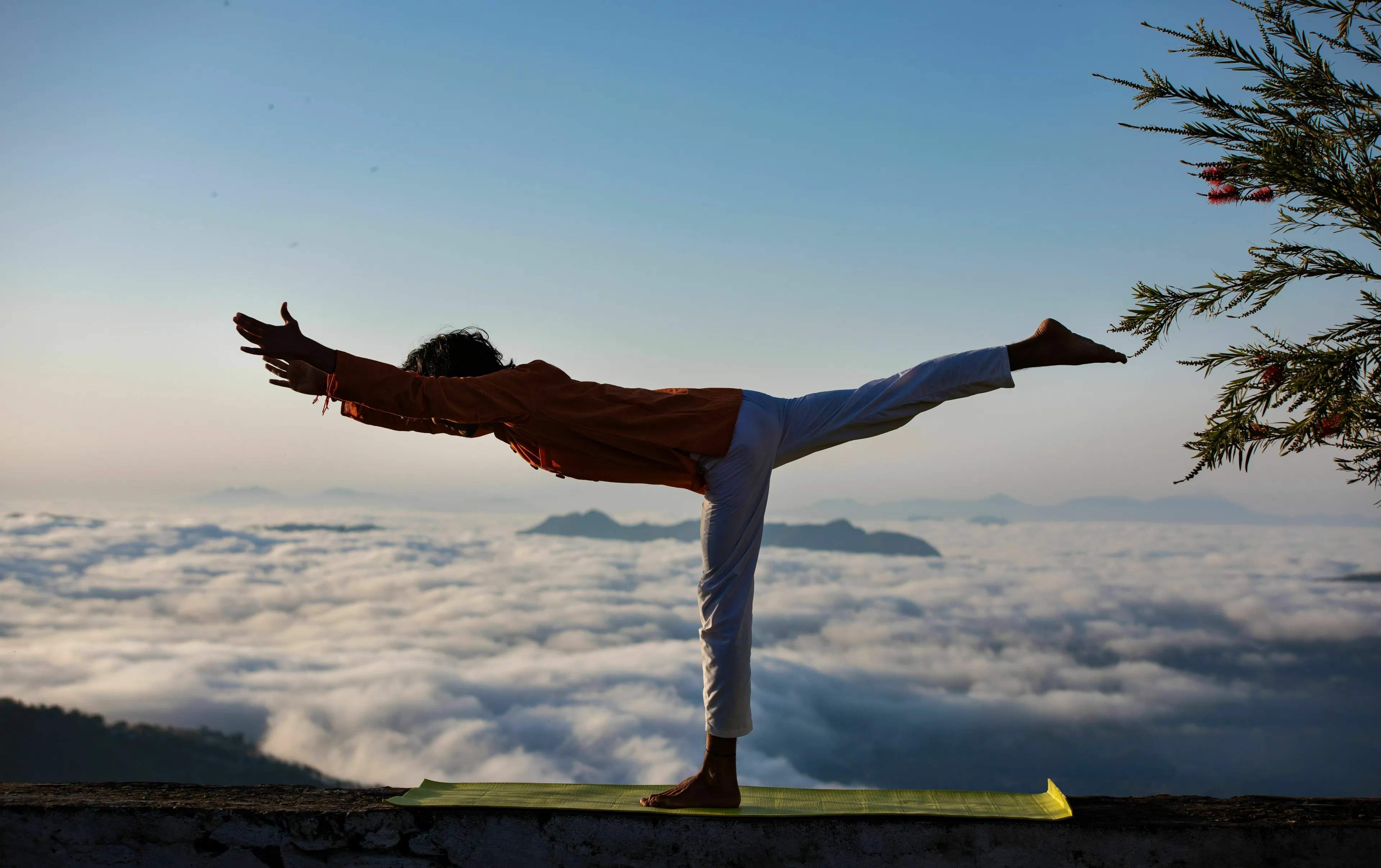Person practicing ancient Indian yoga poses with controlled breathing above clouds.