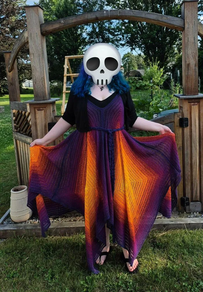 Person wearing colorful crocheted dress with gradient purple and orange hues