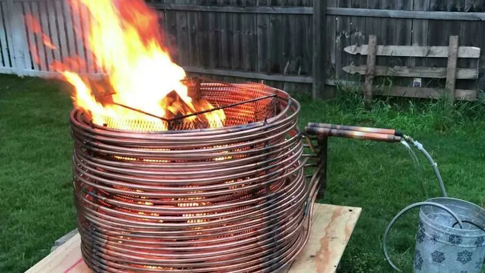 A copper coil fire pit heating water, a clever solution for outdoor comfort made from random junk.