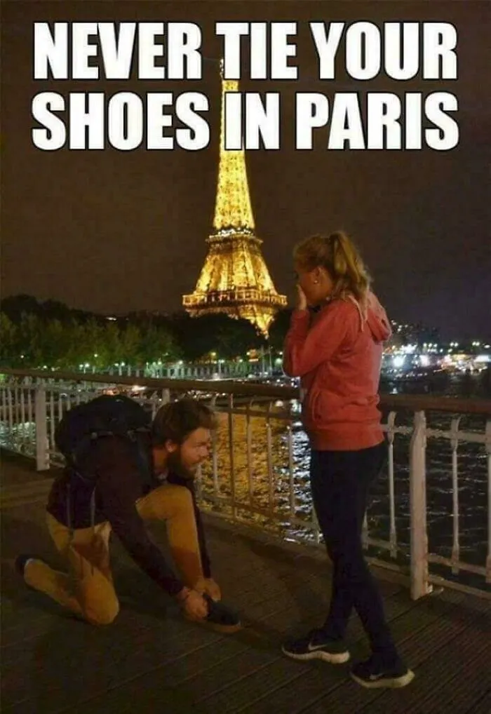 A man tying a woman's shoe in front of the Eiffel Tower, a funny ancient meme.