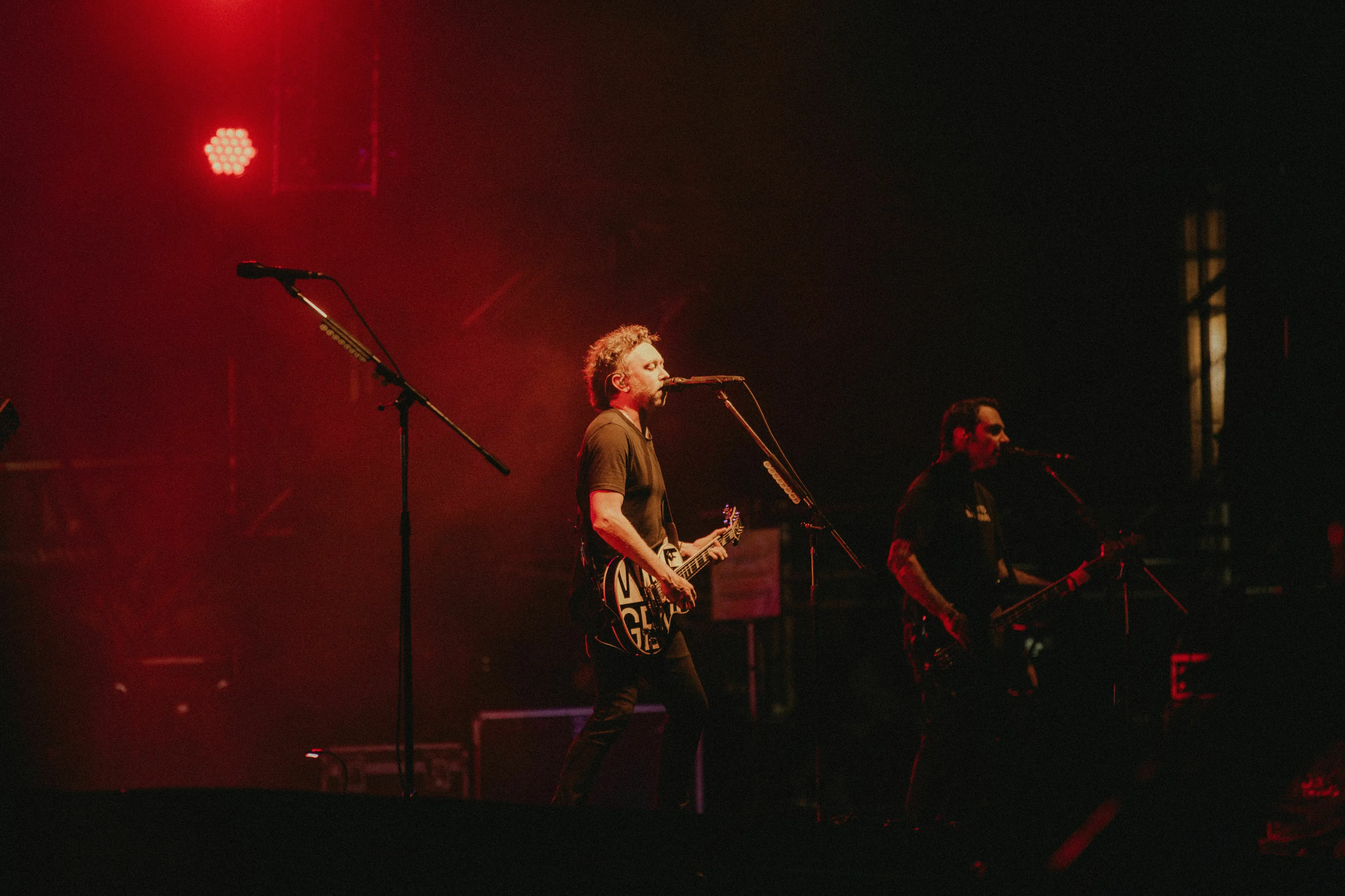 German rock band playing on stage under red lights for a music quiz.