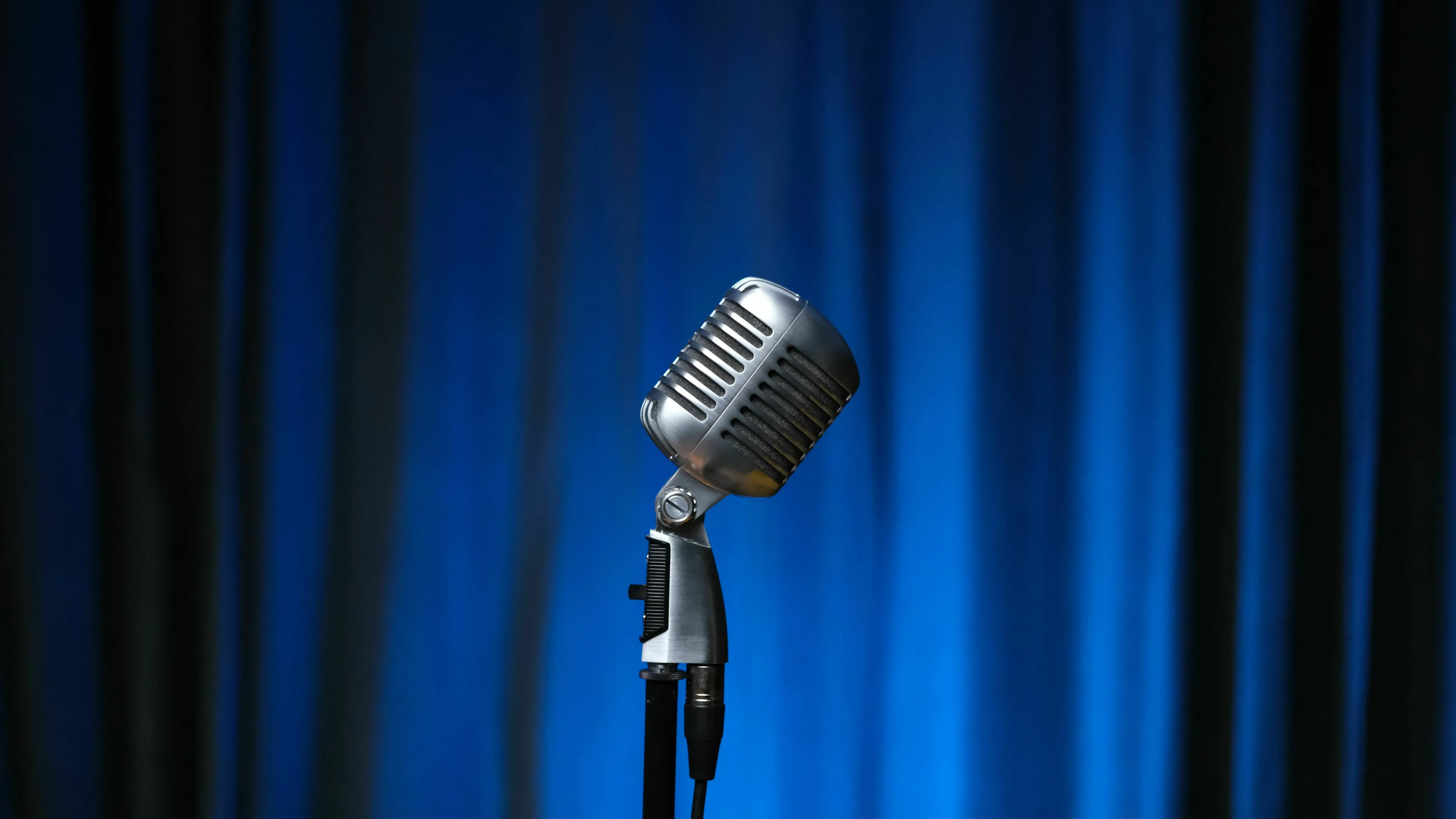 A-To-Z Music Quiz: A vintage microphone on a stand, against a blue curtain, for a 1950s singer.