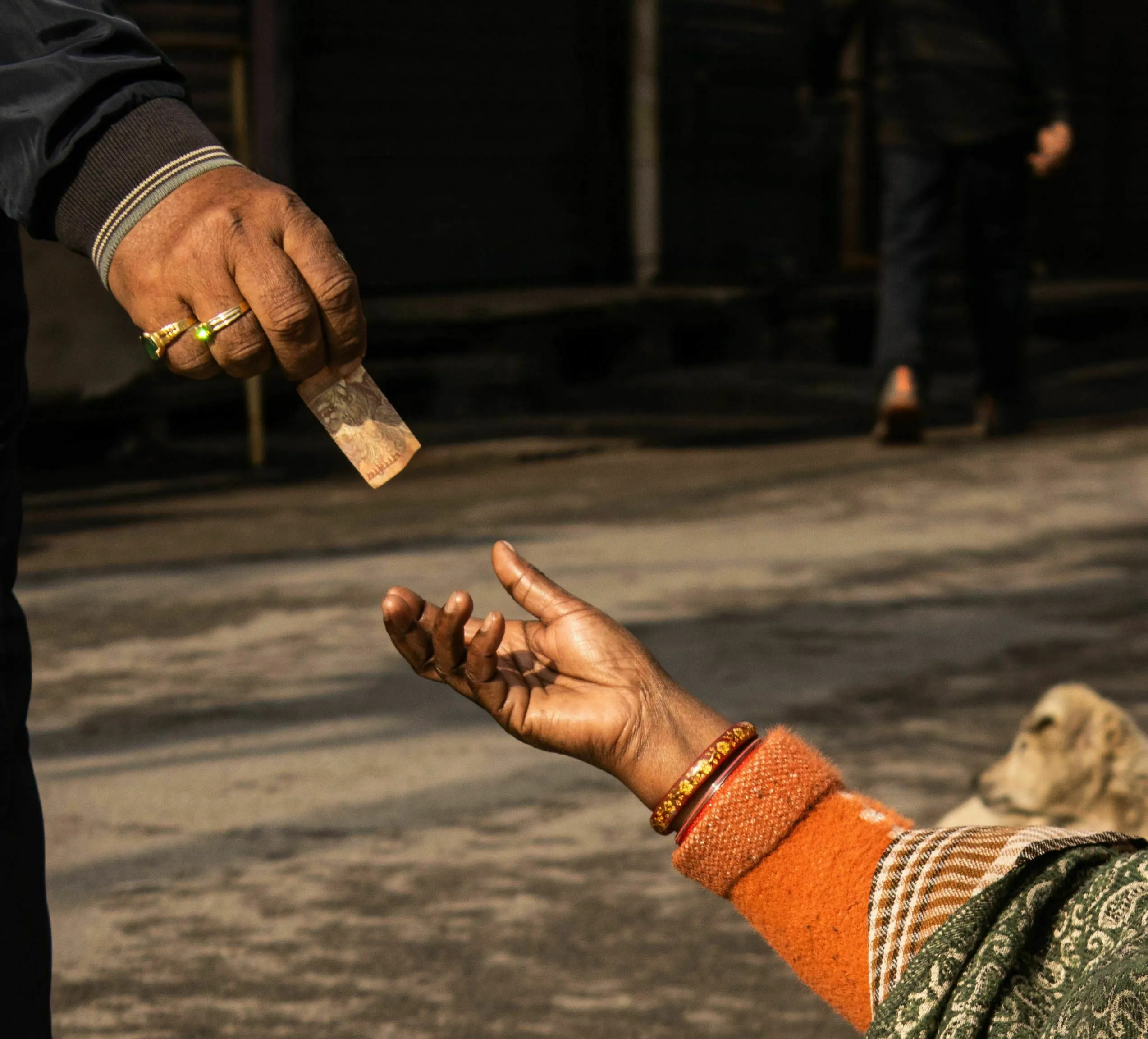 A hand giving money to another hand, representing a mythological quest where a god disguised as a beggar asks for help.