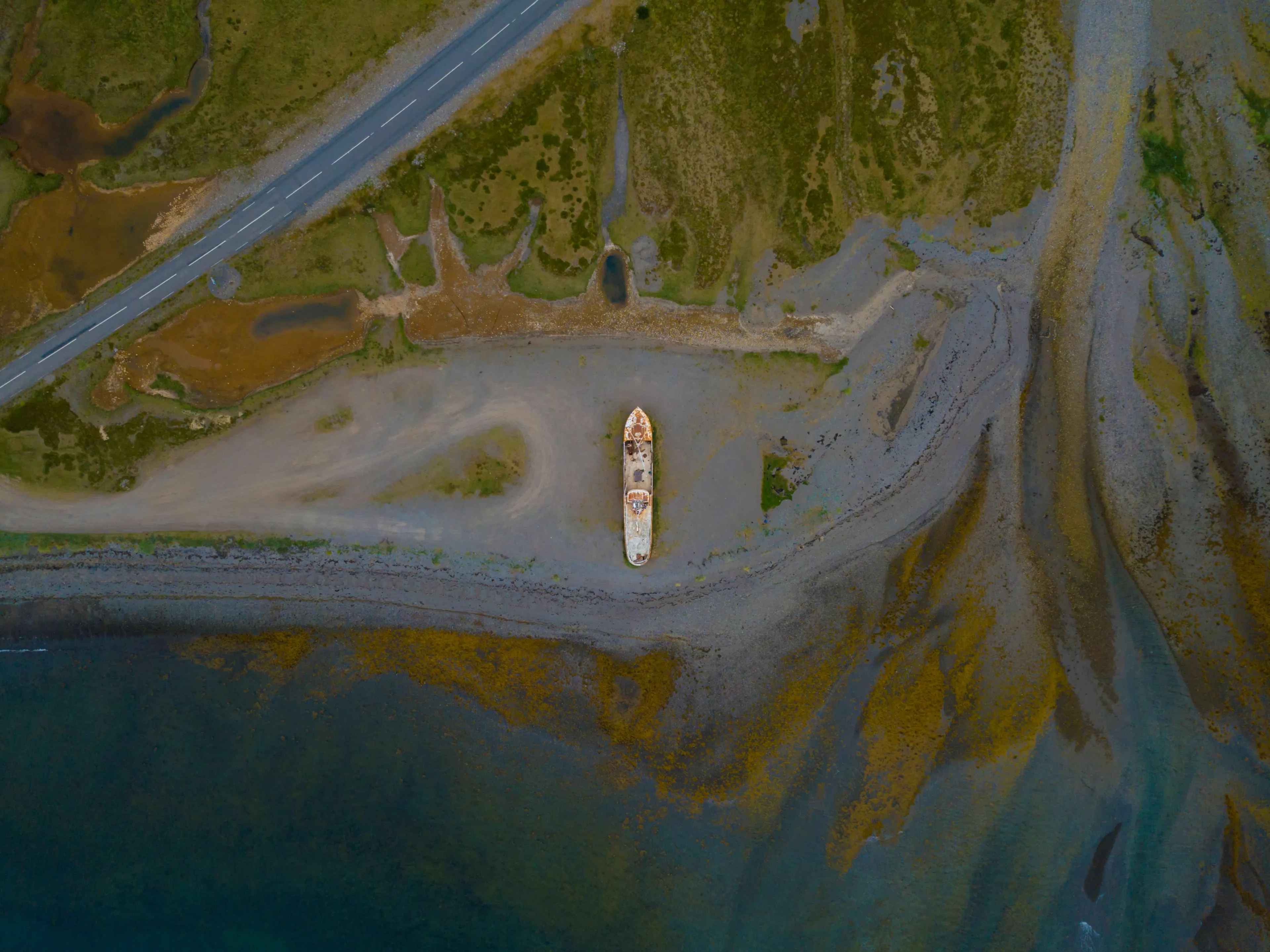 An aerial view of a ship stranded on a mysterious island shore, part of a mythological quest.