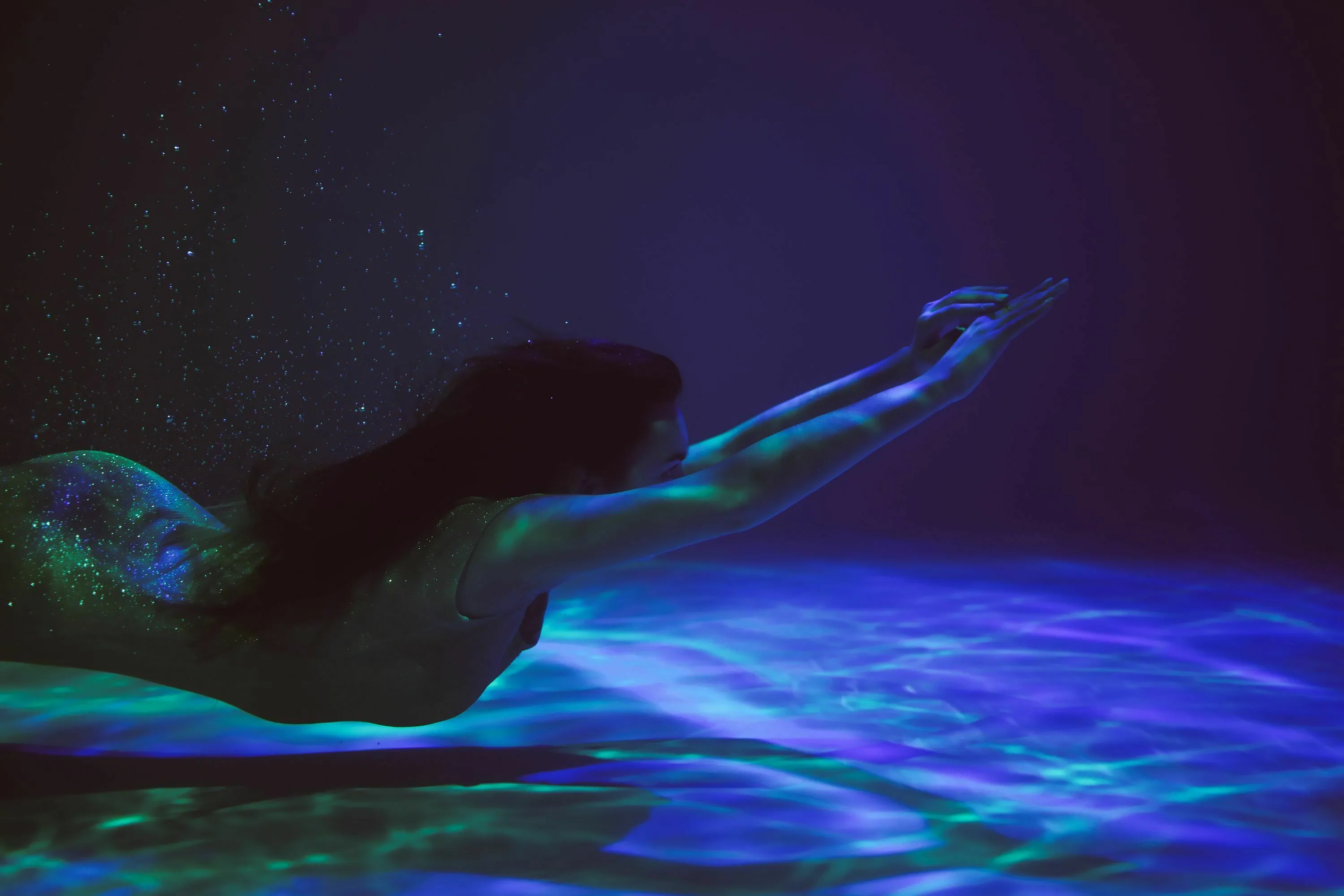 A mythological quest involving a person swimming underwater with glowing light, like a siren.