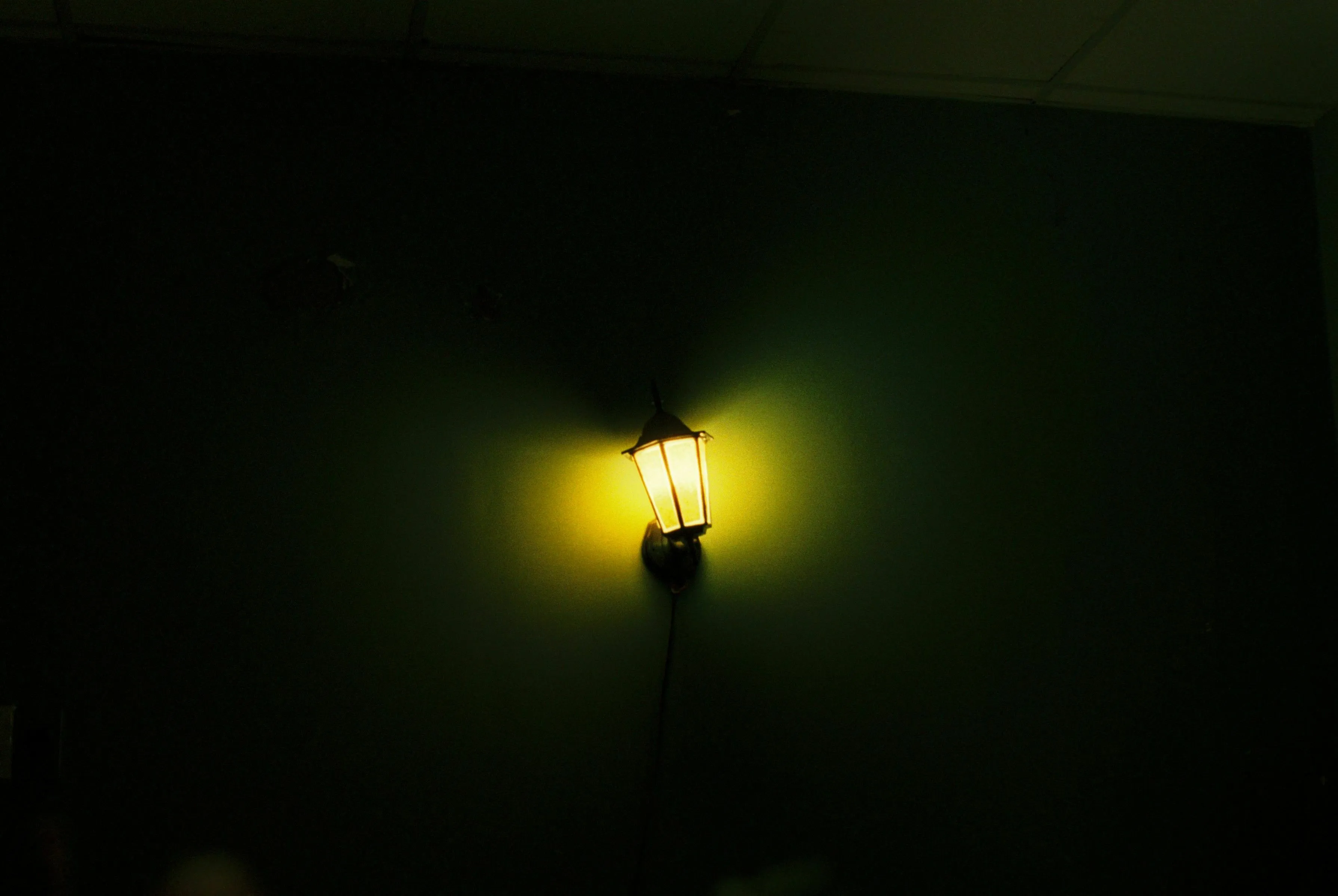A single, dim lantern illuminates a dark wall, symbolizing being unprepared for a final trial in a mythological quest.