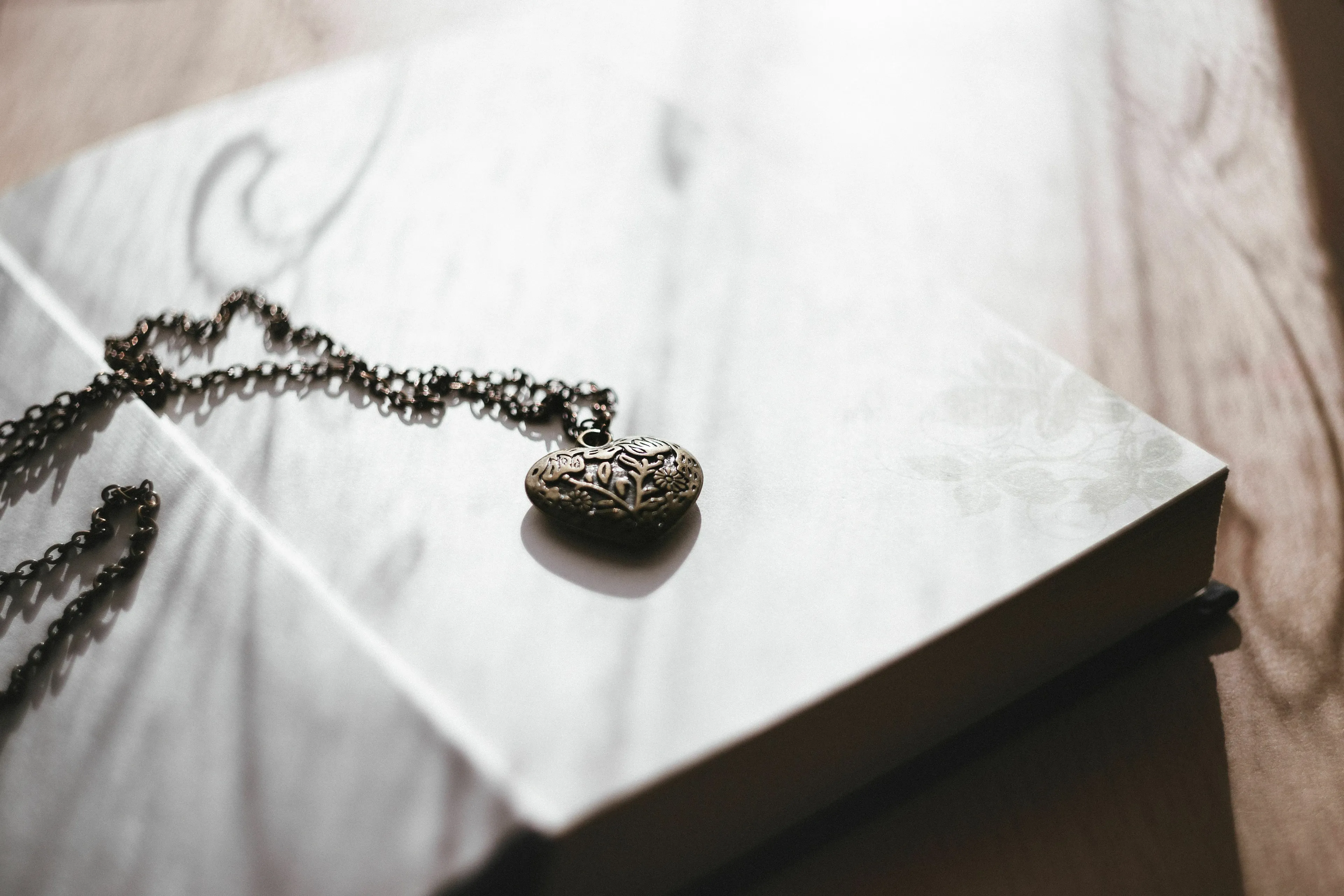 A heart-shaped locket on a book, representing a magic item with a catch in a mythological quest.
