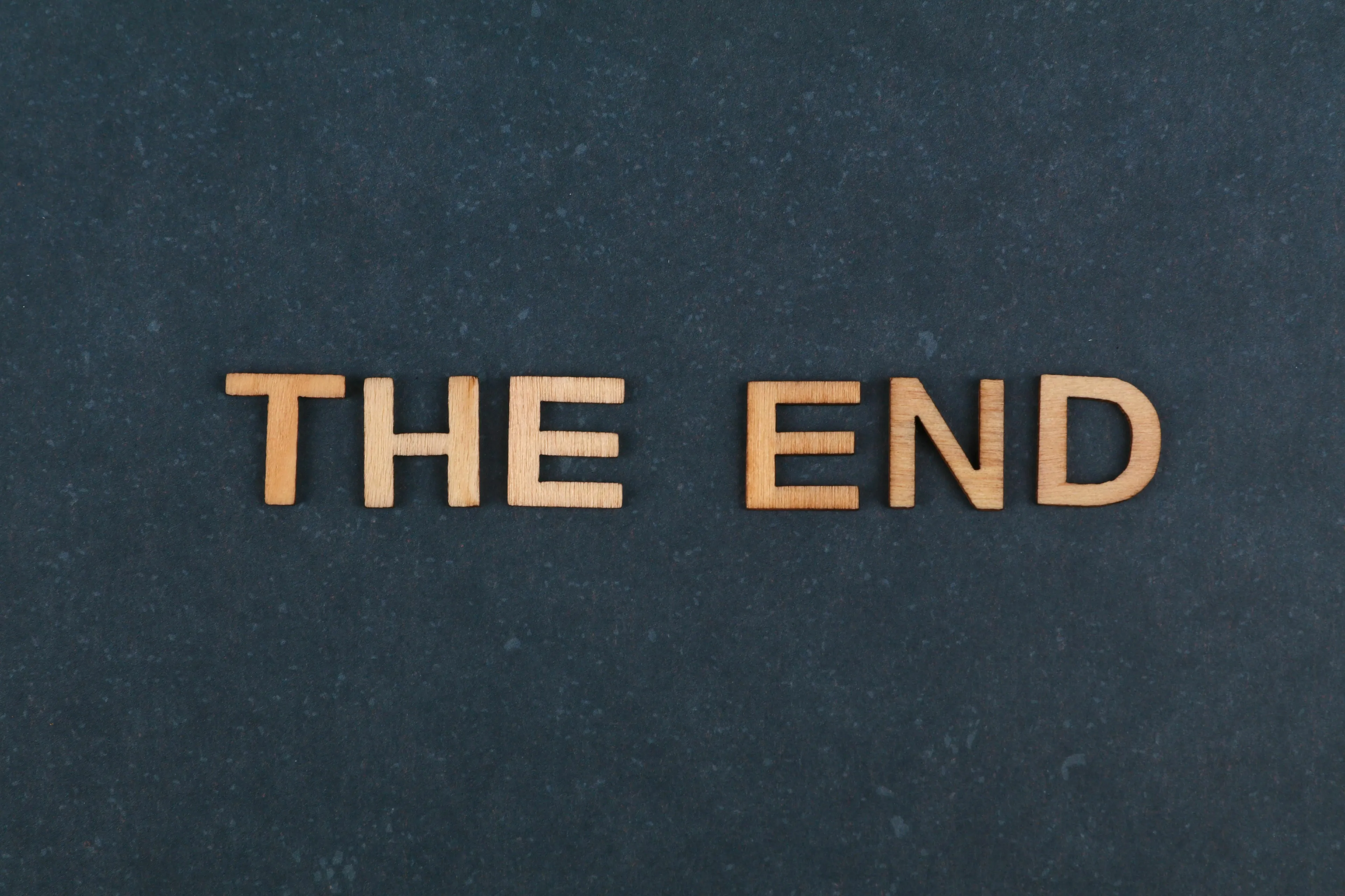 Wooden letters spell THE END on a dark surface, marking the conclusion of a mythological quest and a newfound legend.