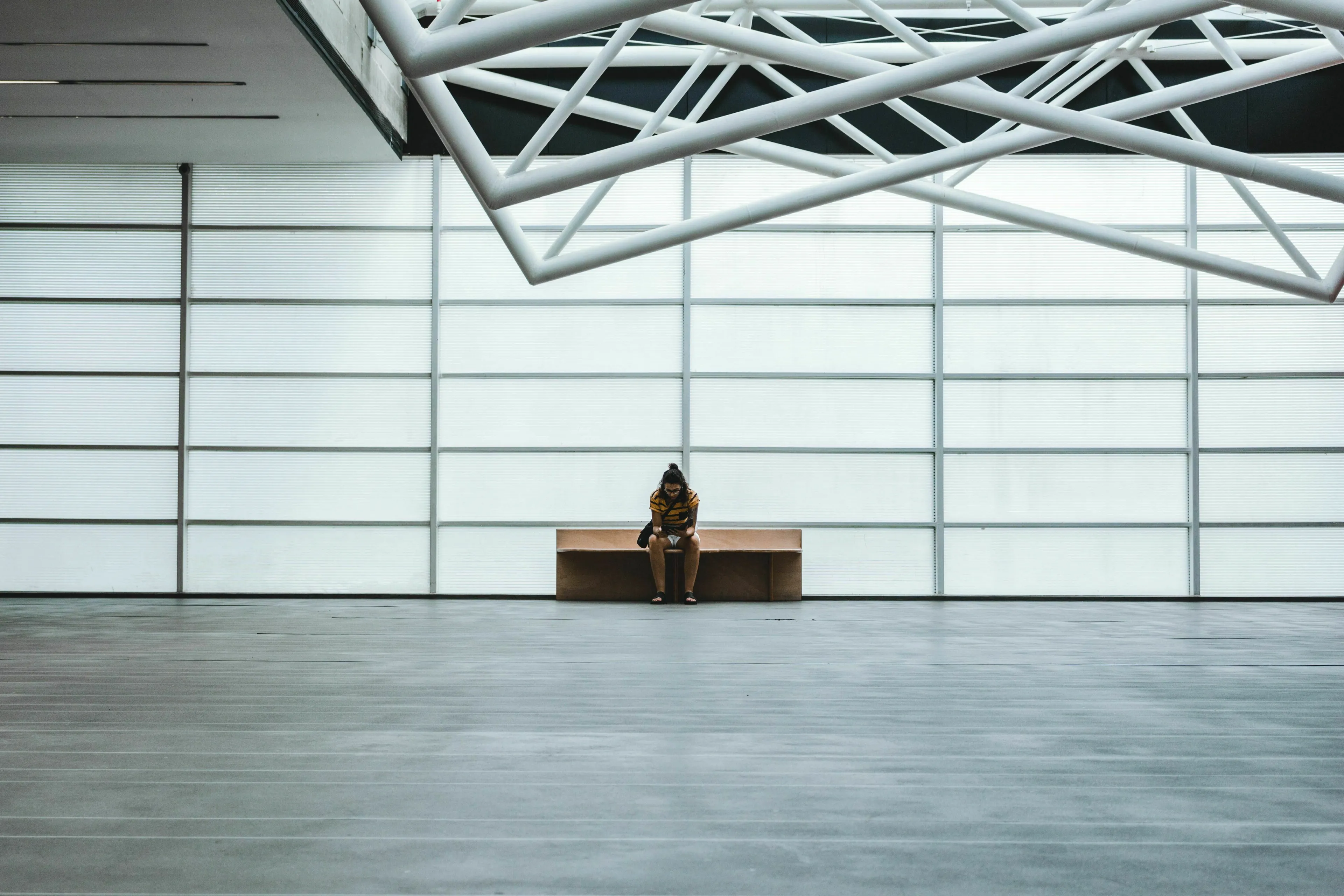 A lone person sits on a bench in a vast, empty hall, waiting early for a green flag event.
