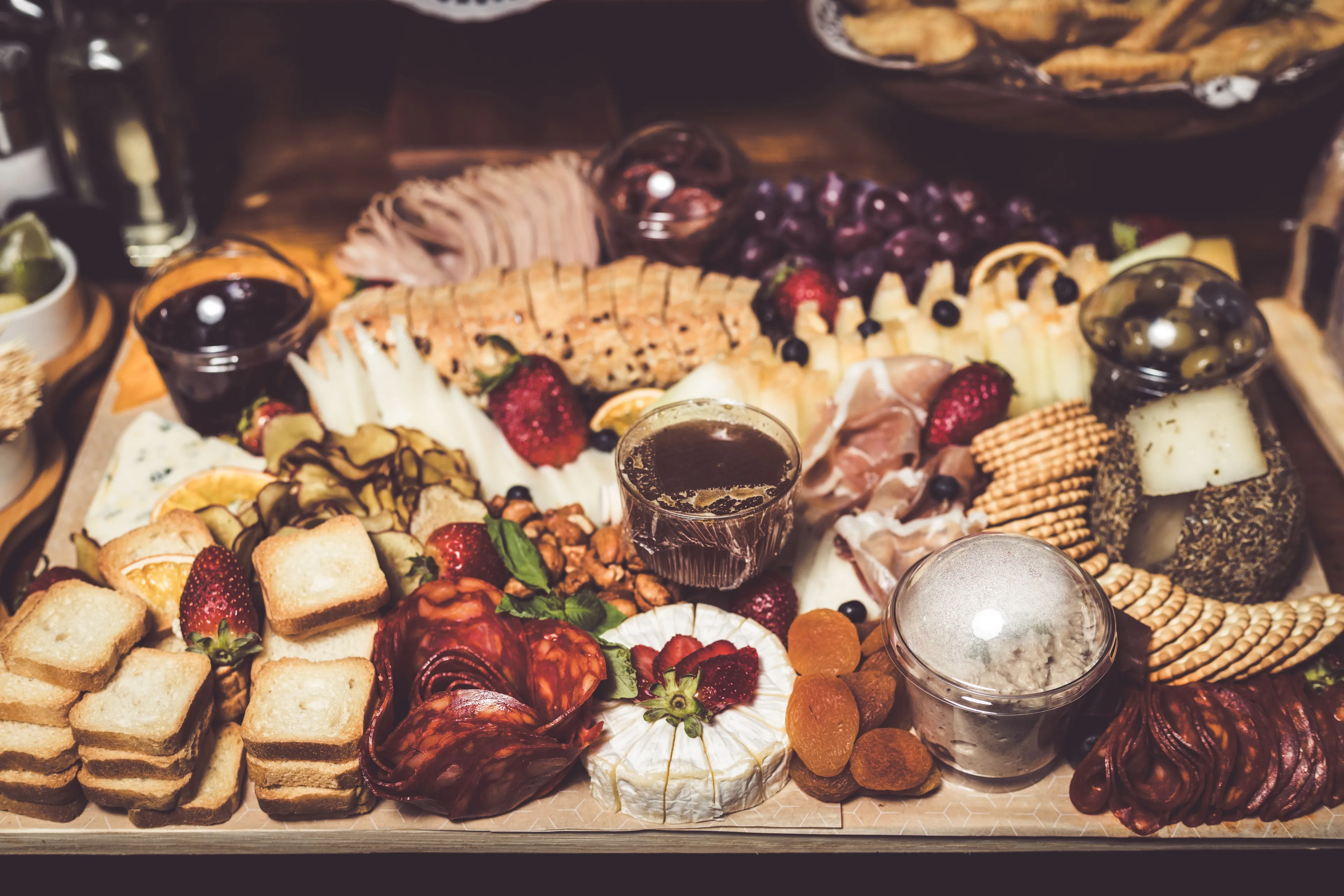 An elaborate charcuterie board overflowing with cheeses, meats, fruits, crackers, and various accompaniments.