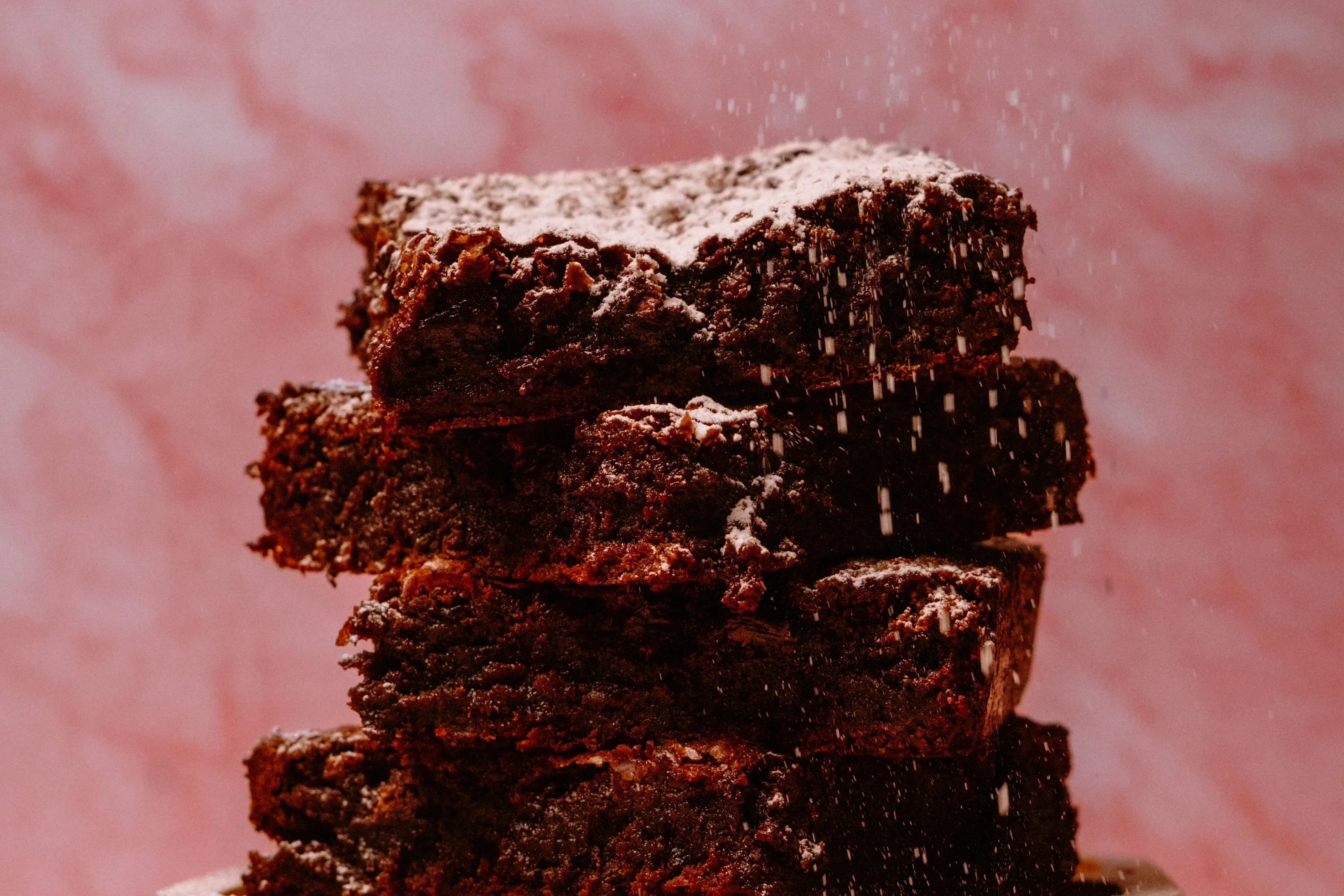 Stack of chocolate brownies with powdered sugar on top.