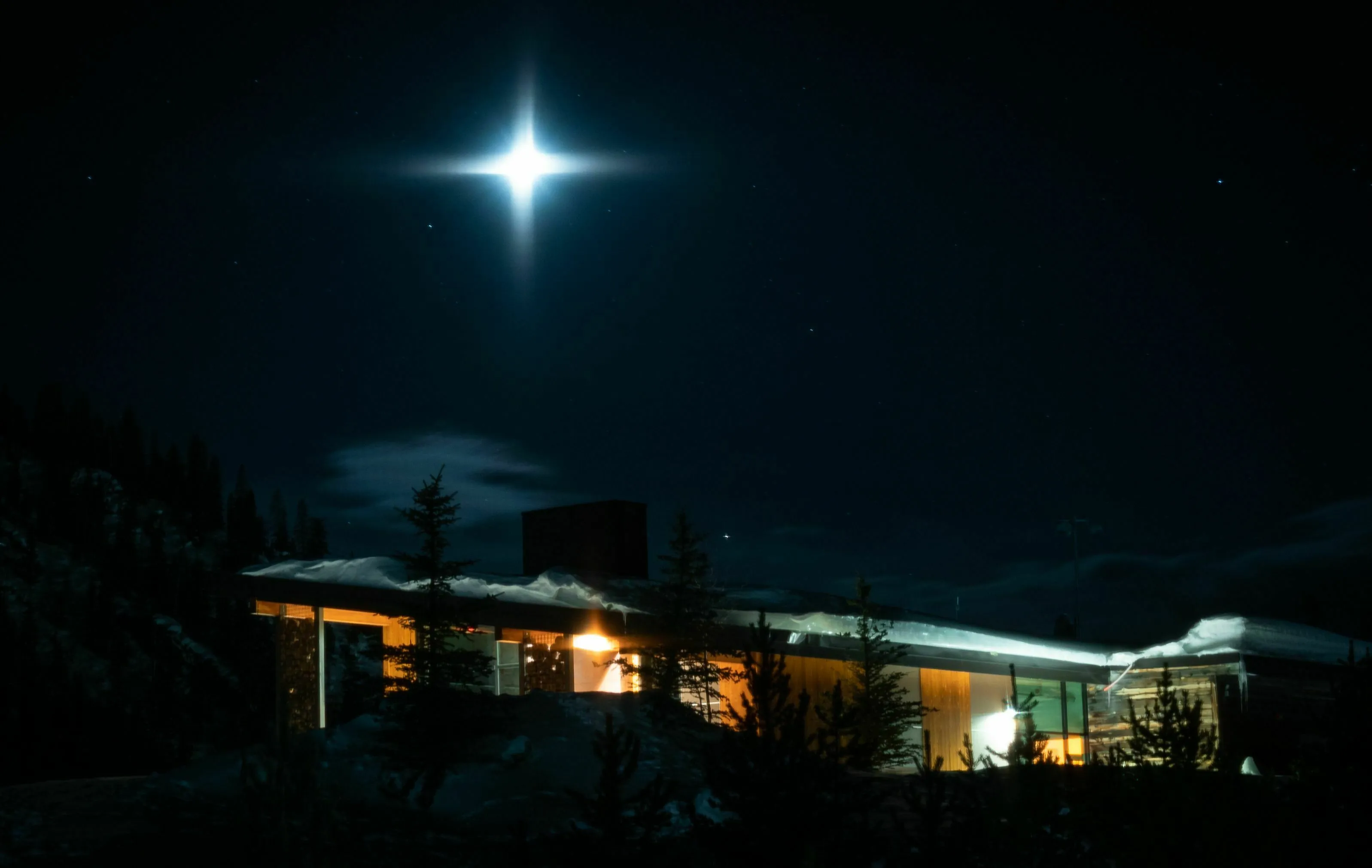 A bright North Star, Polaris, shining above a house in a snowy landscape at night.