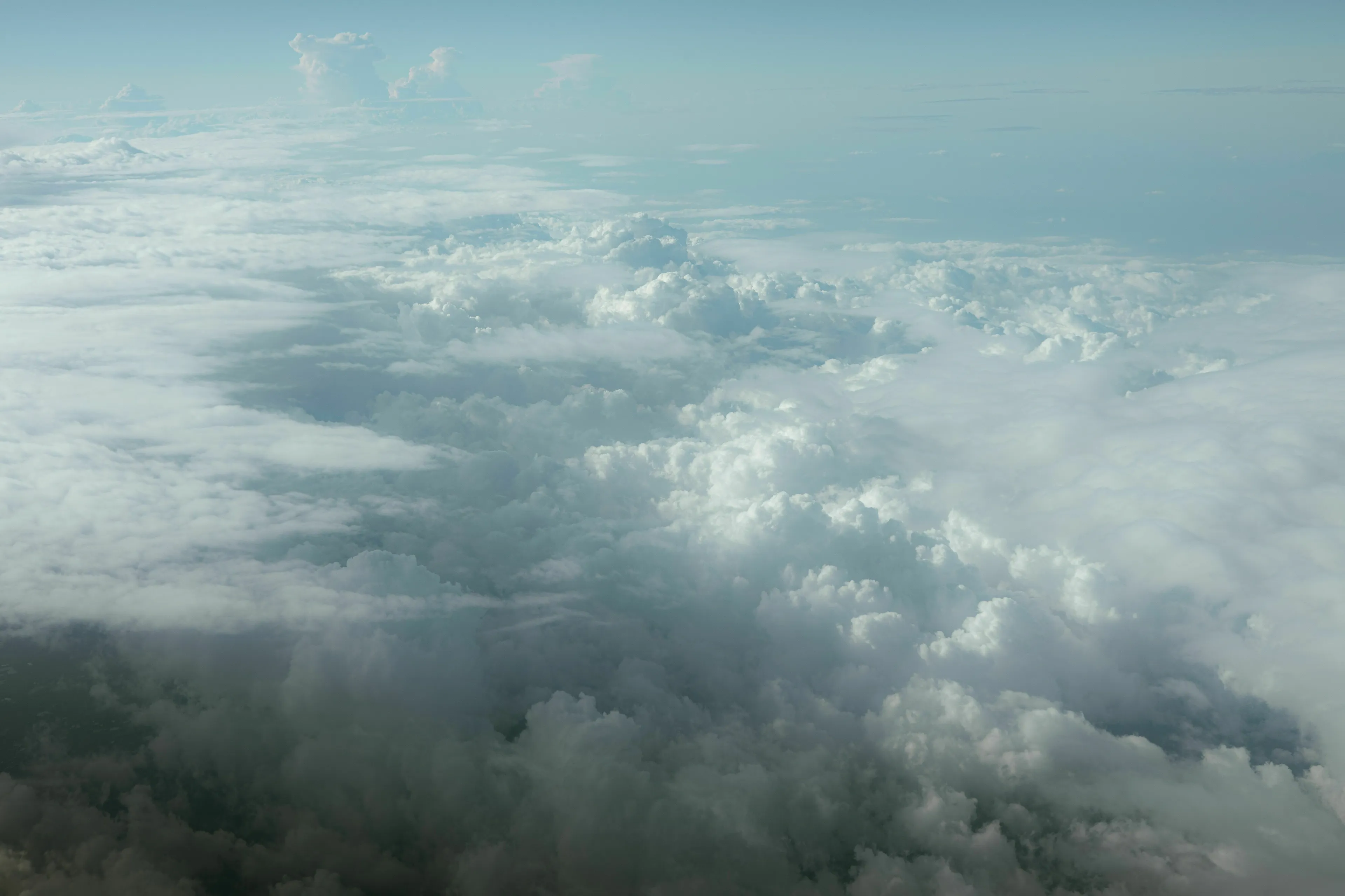 An aerial view of atmospheric pressure clouds from above, with varying densities and heights.