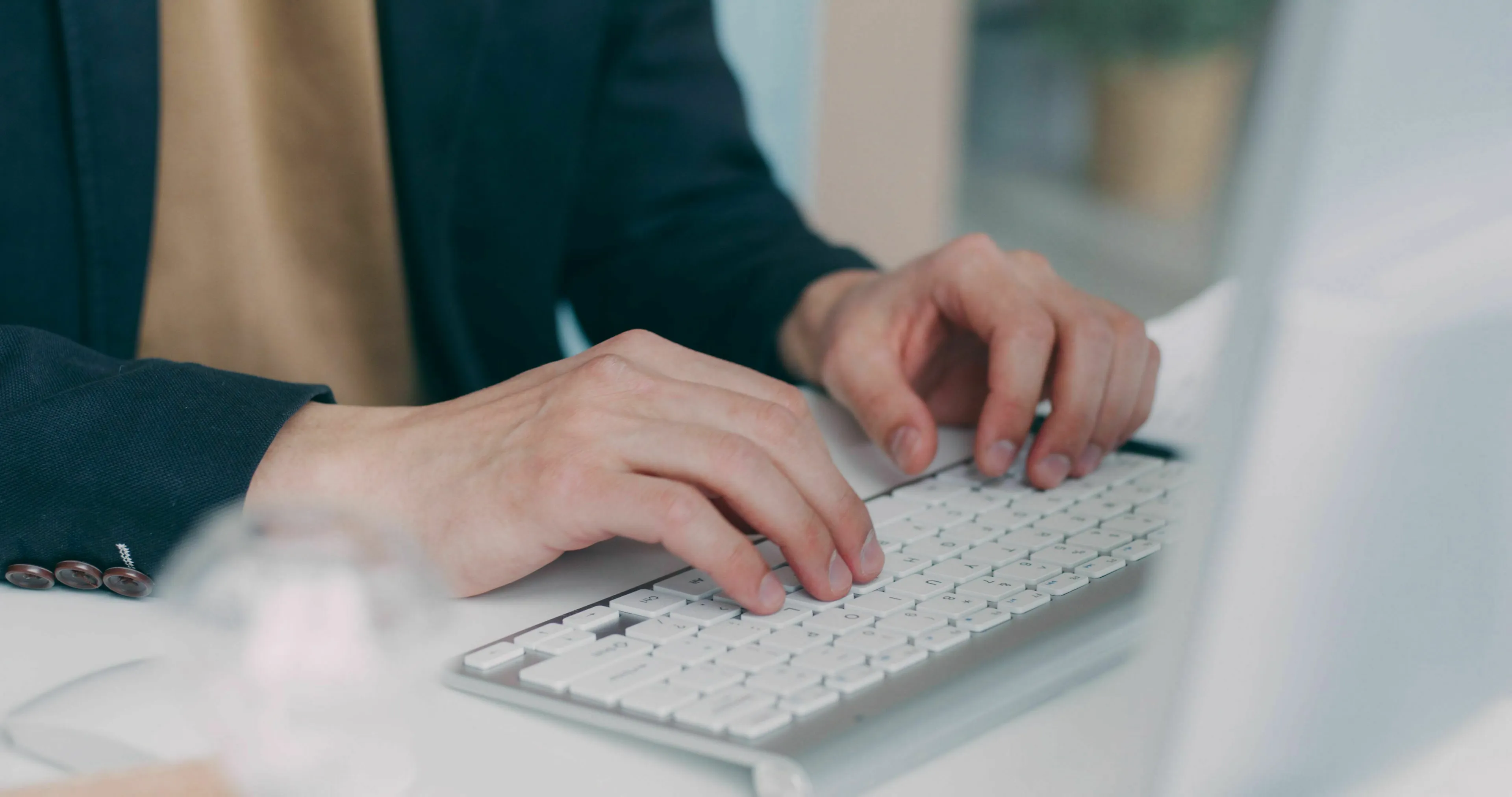 Close-up of hands typing on a white computer keyboard, representing general knowledge about the longest English word.