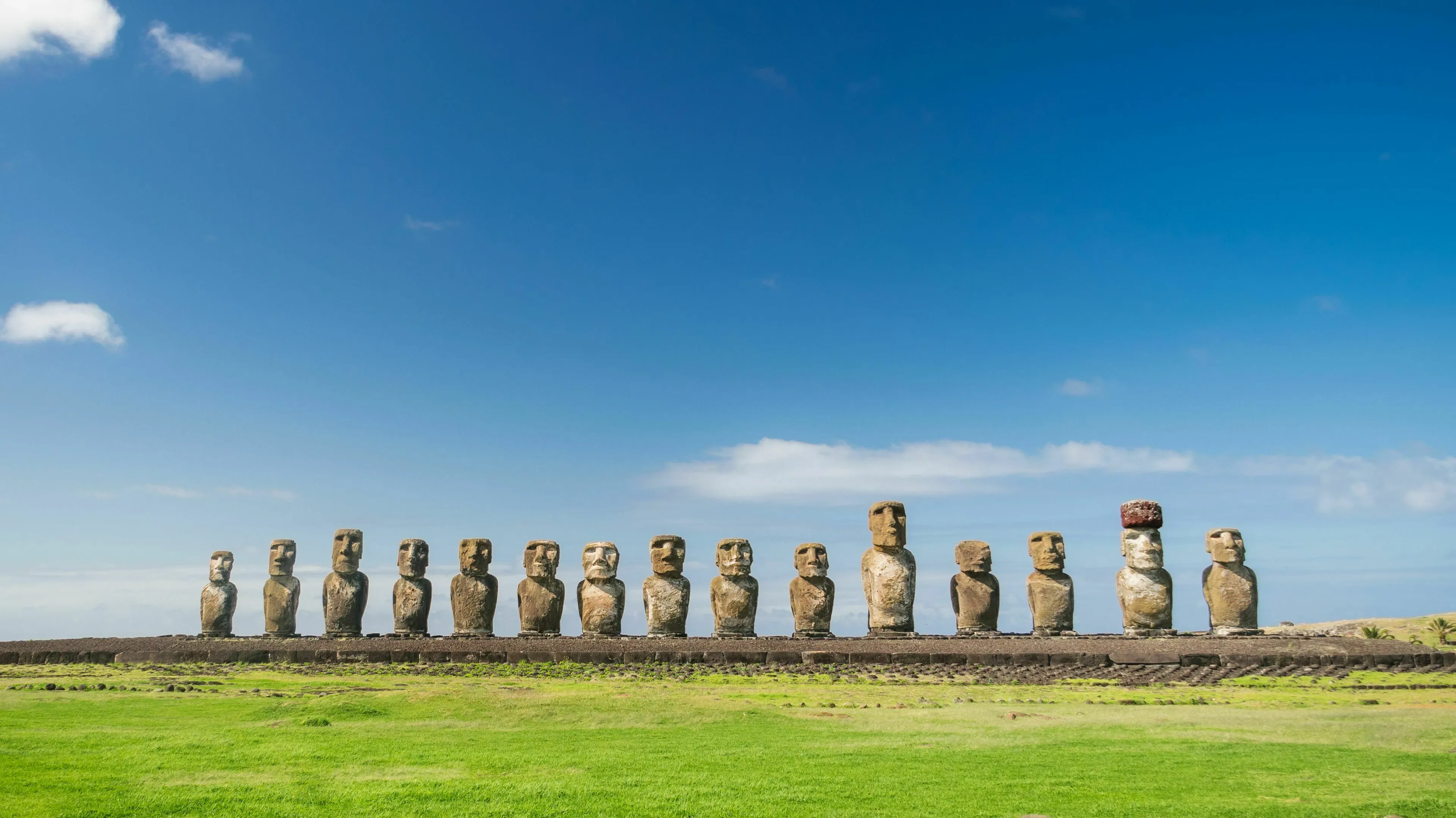 Row of iconic Moai statues on Easter Island, a famous general knowledge landmark in Chile under a blue sky.