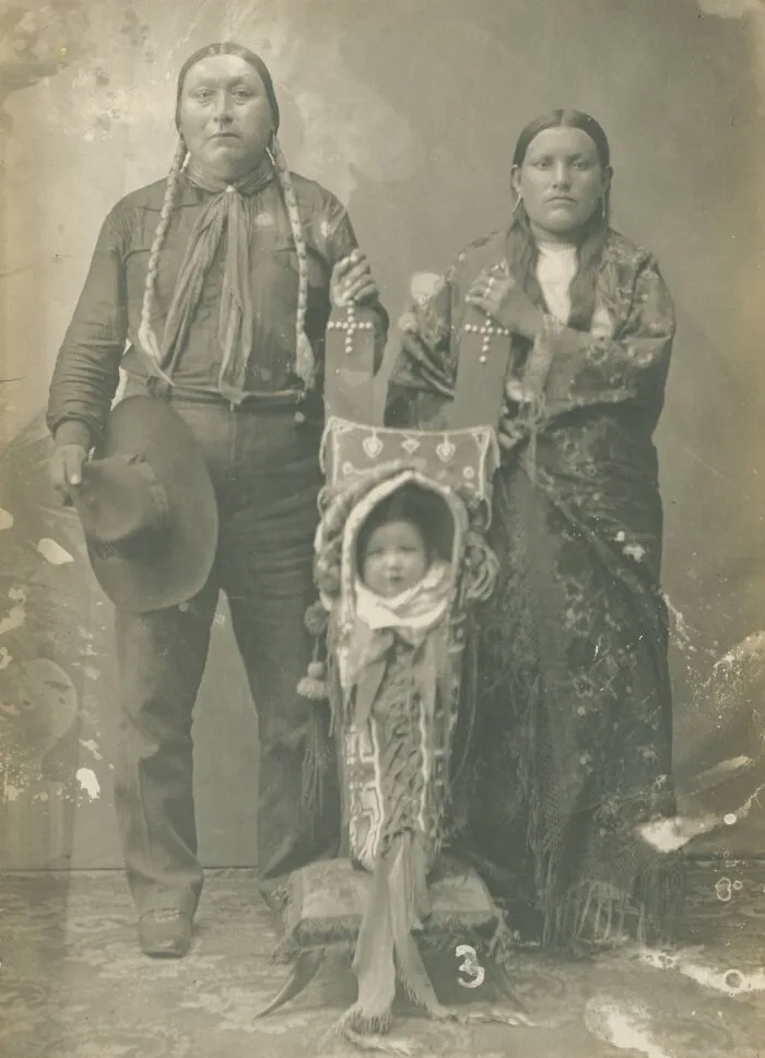 Historical photo of a Native American family with a baby in a cradleboard, showcasing a past culture.