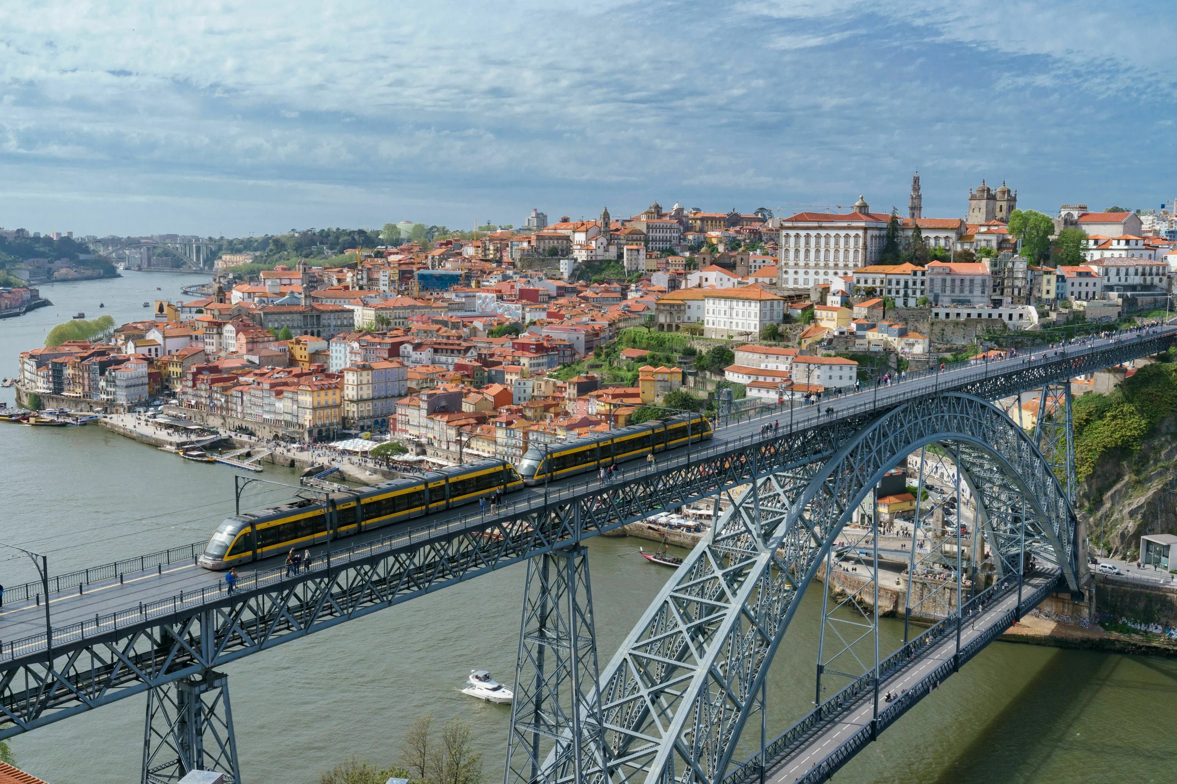 Panoramic view of a city bordering a river, with a large bridge crossing it, showcasing Portugal's landscape.