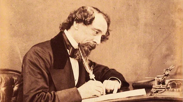 Sepia-toned image of Charles Dickens, a renowned author, writing with a quill pen at his desk.