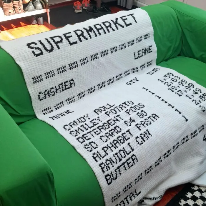 Crochet blanket mimicking a supermarket receipt with black text on white yarn