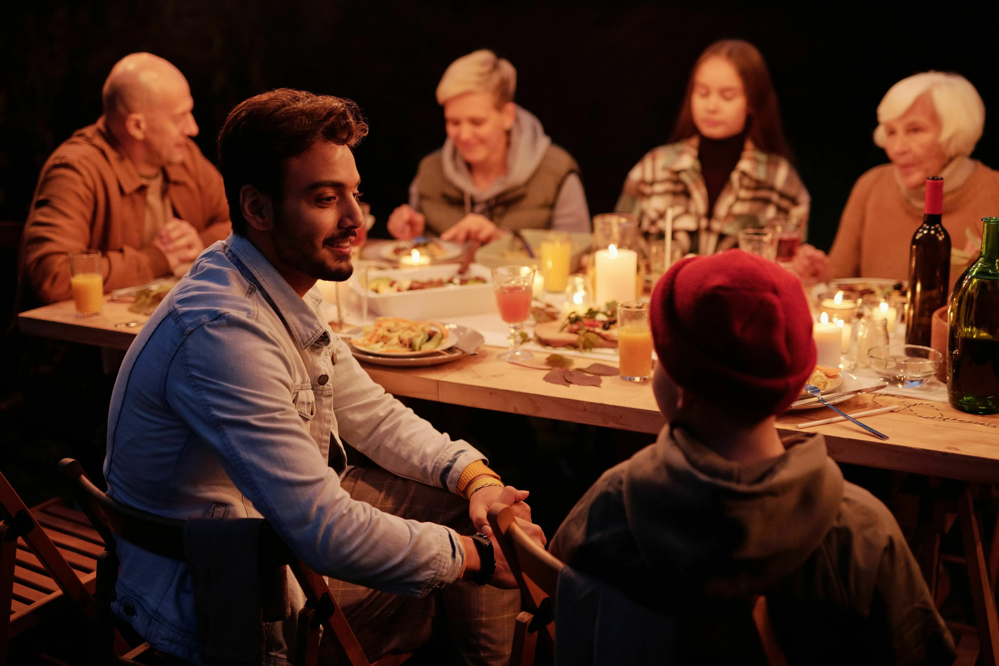 People enjoying a dinner party, lit by candles, engaged in conversation, reflecting what triggers your envy.