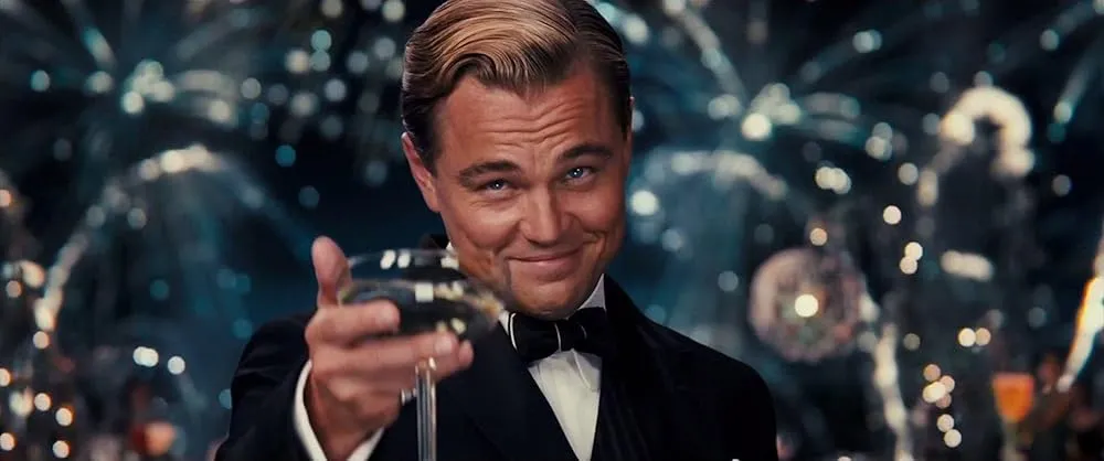 Jay Gatsby in a suit, raising a glass of champagne with a knowing smile, a fictional character to low-key envy.