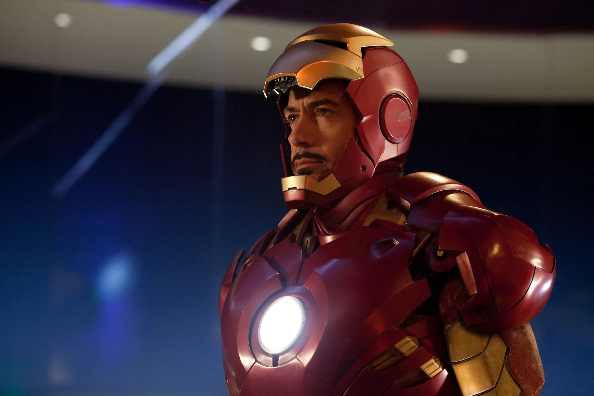 Tony Stark wearing his Iron Man suit helmet partially open, looking thoughtful, a fictional character to low-key envy.