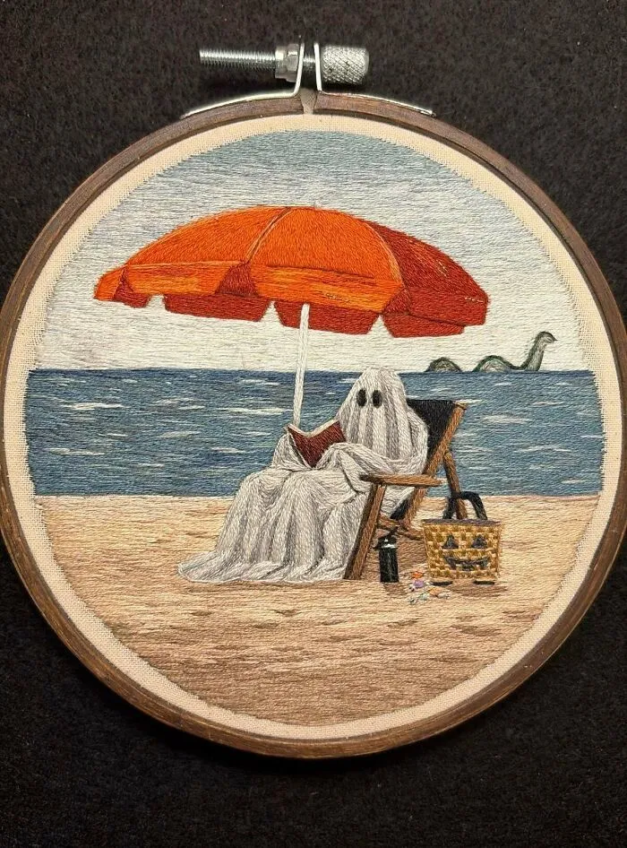 Embroidery project featuring a ghost reading on a beach chair under an orange umbrella