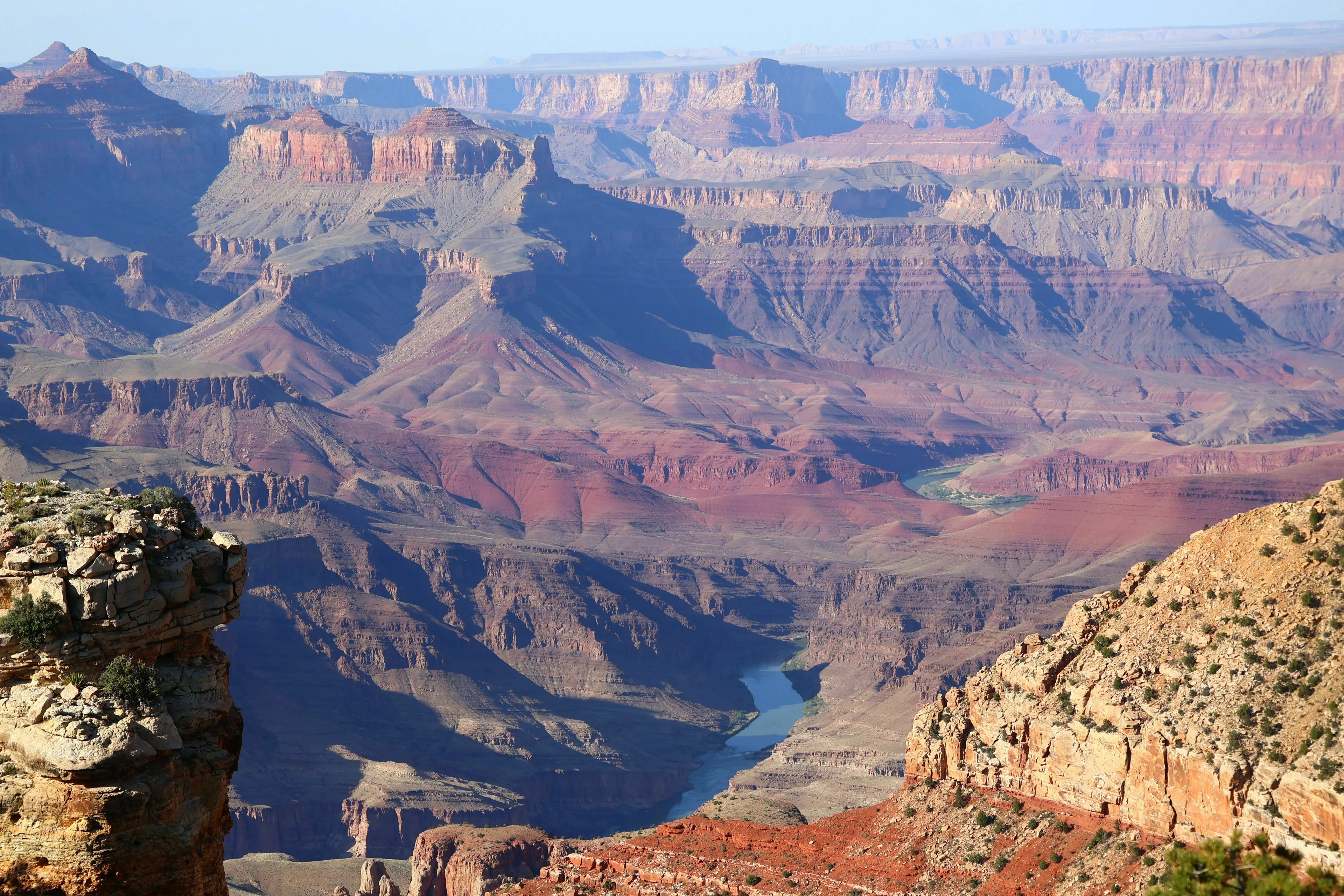 Majestic Grand Canyon landscape with its multi-colored rock layers and a winding river at the bottom.