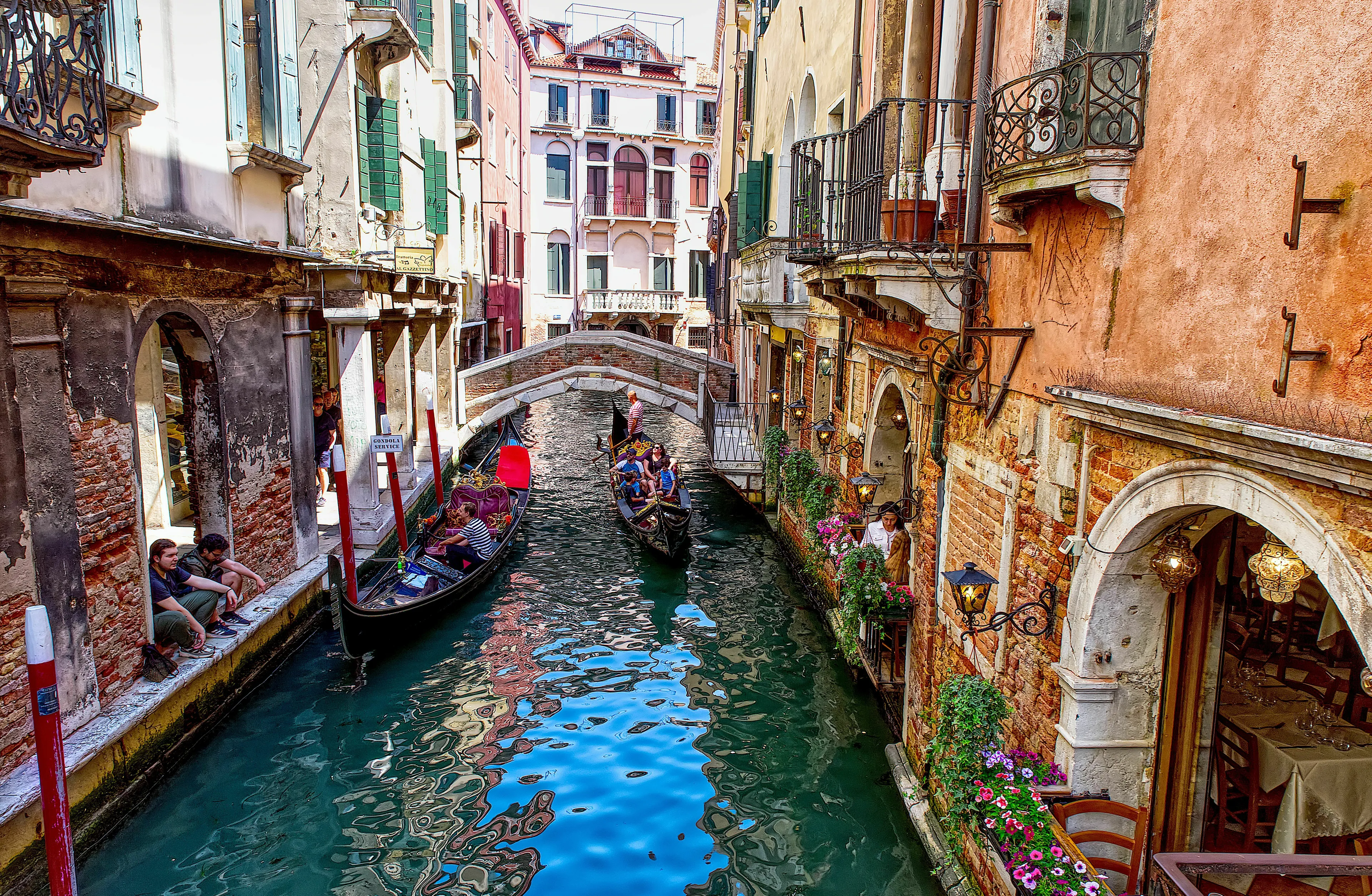 Gondolas on a canal in Venice, Italy, surrounded by historic buildings and bridges, a famous Italian city.
