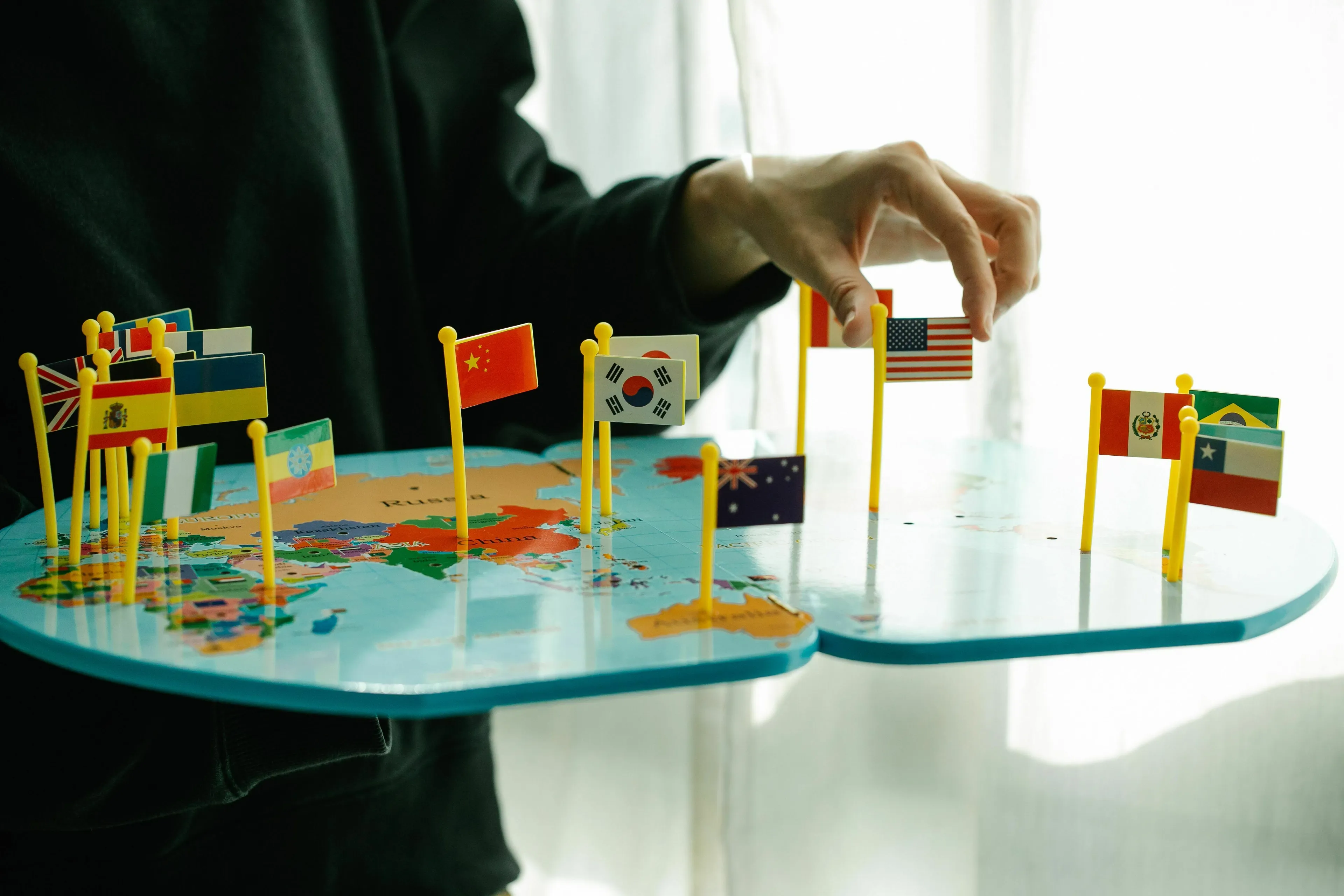 A person placing flags representing different countries on a world map, answering a geography knowledge quiz.